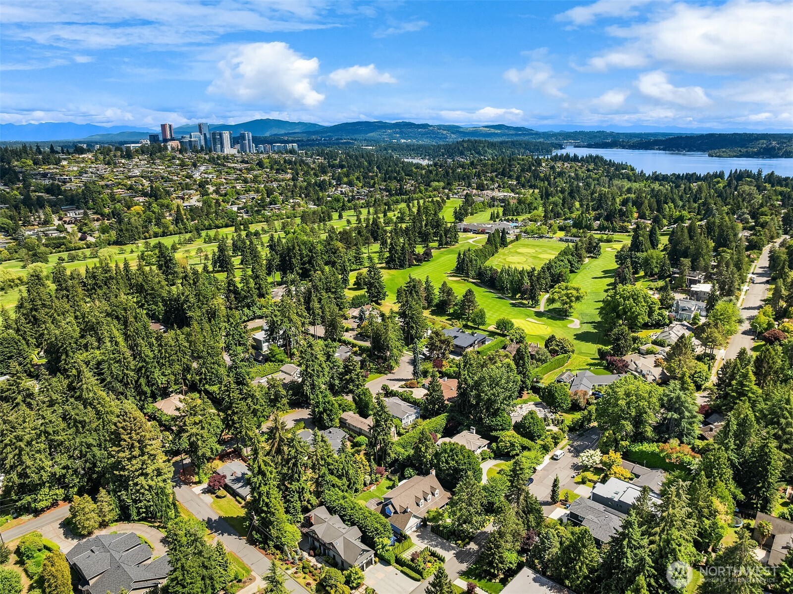 Aerial view showcases the neighboring golf course and bellevue skyline