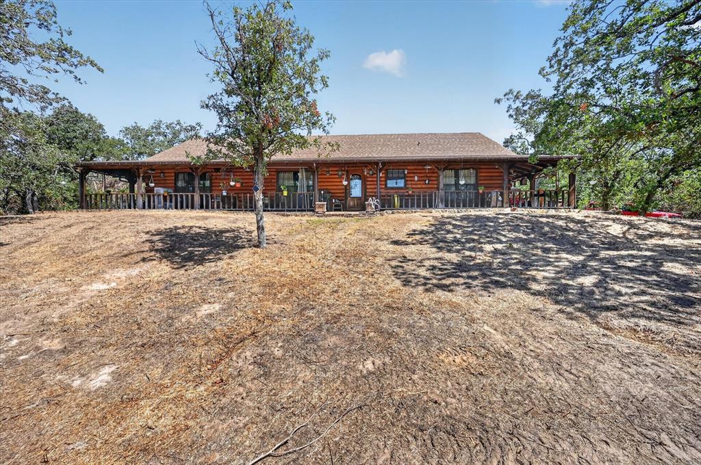 Custom Satterwhite Neches 8in D-log home on 10 acres in Springtown. Built 2003, 2,436 SF, 3BR-2BA, with a full wraparound covered porch and mature oaks. Interior is 90% tongue-and-groove wood with exposed wood beams, alderwood doors, and blue pine and aspen accents in two bedrooms and a bath. Vaulted great room features a Majestic wood-burning fireplace and Velux skylights. Kitchen and primary bath offer custom cabinetry, a reproduction antique-style electric range, and sawn, stained, and sealed concrete floors throughout. Primary suite includes a jetted triangle soaking tub, rain-head and body-jet shower, and dual walk-in closets. 10x24 sunroom addition with a 2-year-old mini-split, two Velux skylights, and tile floor. Wireless home automation and outdoor speakers. New Class 3 CertainTeed roof (May 2026), 3-zone radiant in-floor heat, and a 5-ton heat pump. 25x30 metal garage with two 10x10 roll-up doors, a 4.2kW 48V off-grid solar system (ground-mount sun-seeking and roof-mount panels, 300Ah battery backup), a 220V EV charger, and concrete driveways. Attached 2-car garage plus 2-stall carport, a 12x24 cedar tongue-and-groove workshop with AC and 220V electric, and two 12x12 finished storage rooms. Barn with four finished 10x10 stalls, a 10x10 tack room, water, and 200-amp electric; second drywalled outbuilding with wood floor; a small metal barn and metal shed, both with elec; additional carports throughout the barnyard. Manual backup generator with transfer switch and three separate 200-amp electric services to outbuildings. Private well (~300 ft, Trinity River Basin), aerobic septic with new 2026 controller and aerator, 4-zone WiFi irrigation, 50-gallon Polaris propane water heater, Starlink internet (primary and standby), property-wide security cameras, and gated electric entry. 5 acres cross-fenced with no-climb and 4-board white vinyl fencing plus barnyard pens, suited for horses or livestock. A rare blend of craftsmanship, systems, and acreage.