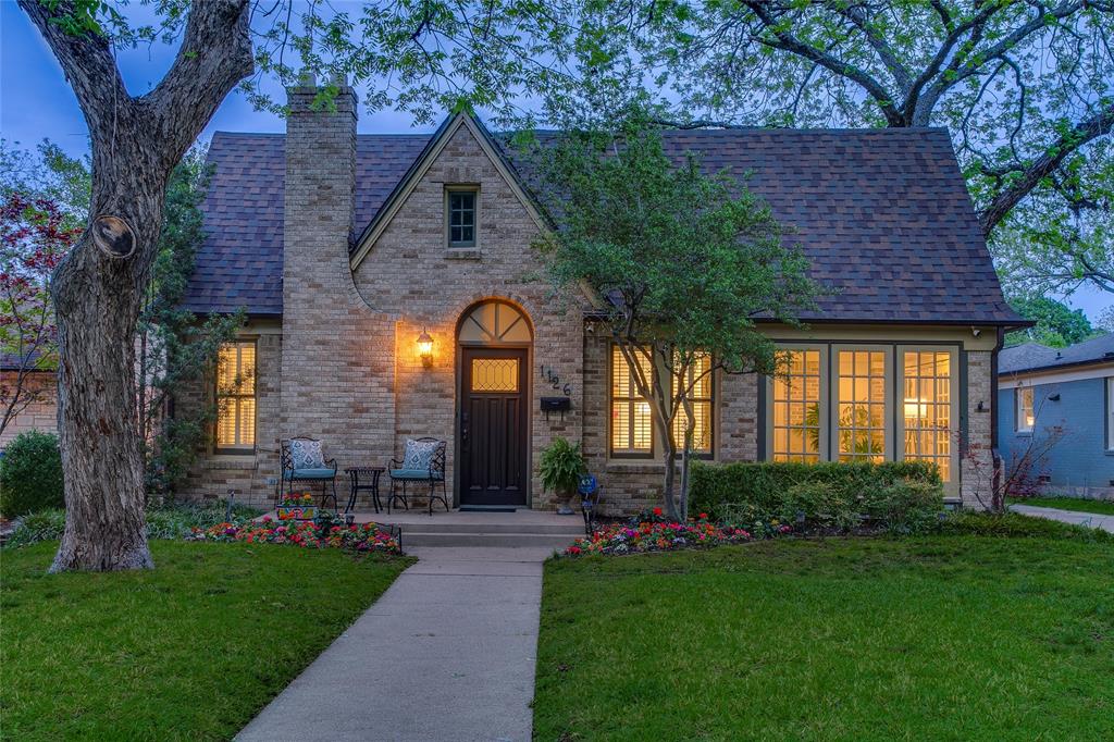 Beneath a canopy of mature trees in Kessler Park, this updated Tudor unfolds with a sense of calm that feels both rooted and refreshed. The approach is timeless, with classic brickwork and soft landscaping setting a quiet tone. Inside, original hardwood floors ground the interiors while natural light moves easily across a softened palette. The living space feels composed and inviting, with a reimagined fireplace adding texture without overpowering the room. The layout flows with intention. A front living area connects to a secondary sitting space, offering flexibility for how you gather or unwind. Just beyond, a sunlit bedroom perfect as an office and wrapped in windows brings in soft daylight and views of the trees, creating a natural place for work or quiet moments. The kitchen blends classic structure with thoughtful updates. Custom cabinetry, warm stone surfaces, and stainless appliances are paired with a deep green tile backsplash that adds depth and contrast. It’s functional, well-scaled, and connected to the dining area where light pours in through oversized windows. Bedrooms feel calm and balanced, with soft tones and natural light. The primary suite offers a more private retreat with direct access to the backyard, creating a seamless connection between indoor and outdoor living. Bathrooms carry a mix of traditional materials and subtle updates. Outdoors, a curved pool and spa anchor the backyard, framed by lawn, stone, and mature trees that create both openness and privacy. A covered patio extends the living space, offering a place that shifts easily from morning coffee to evenings under soft light. Just moments from Bishop Arts and Stevens Park Golf Course, the home offers connection without sacrificing its sense of retreat. A place where light, layout, and outdoor living come together in a way that feels natural, livable, and quietly complete.