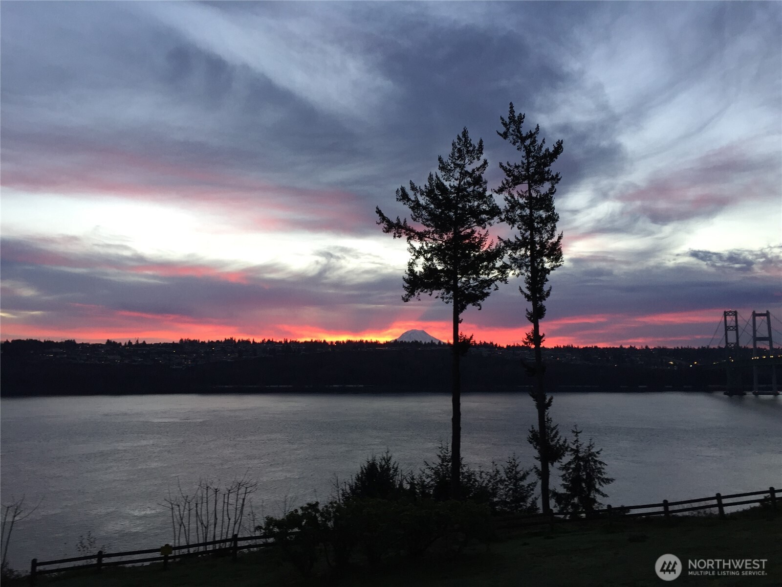 Finally, a ground-floor condo with wide open views of the Narrows strait, Mount Rainier, and the Narrows Bridge. Exceptional location minutes from the new PenMet Parks Rec Center, Cushman Trail, Hwy 16, Downtown Gig Harbor, Narrows Beach, and shopping and dining. Ground-level entry with main-floor living and abundant storage. Enjoy community amenities: hiking trails, outdoor pool and hot tub, clubhouse, and secure gated entry. Morning sunrises, evening city lights, and moonglade on clear nights are visible from the living room and primary suite. Watch migrating orcas and resident eagles nearby. Comfort features include radiant heat plus four ductless mini-split units for supplemental heating and cooling. Gardeners will delight in the drip irrigation on the back deck and front patio for plantings. Bonus: seller will pay the first year of HOA dues!
