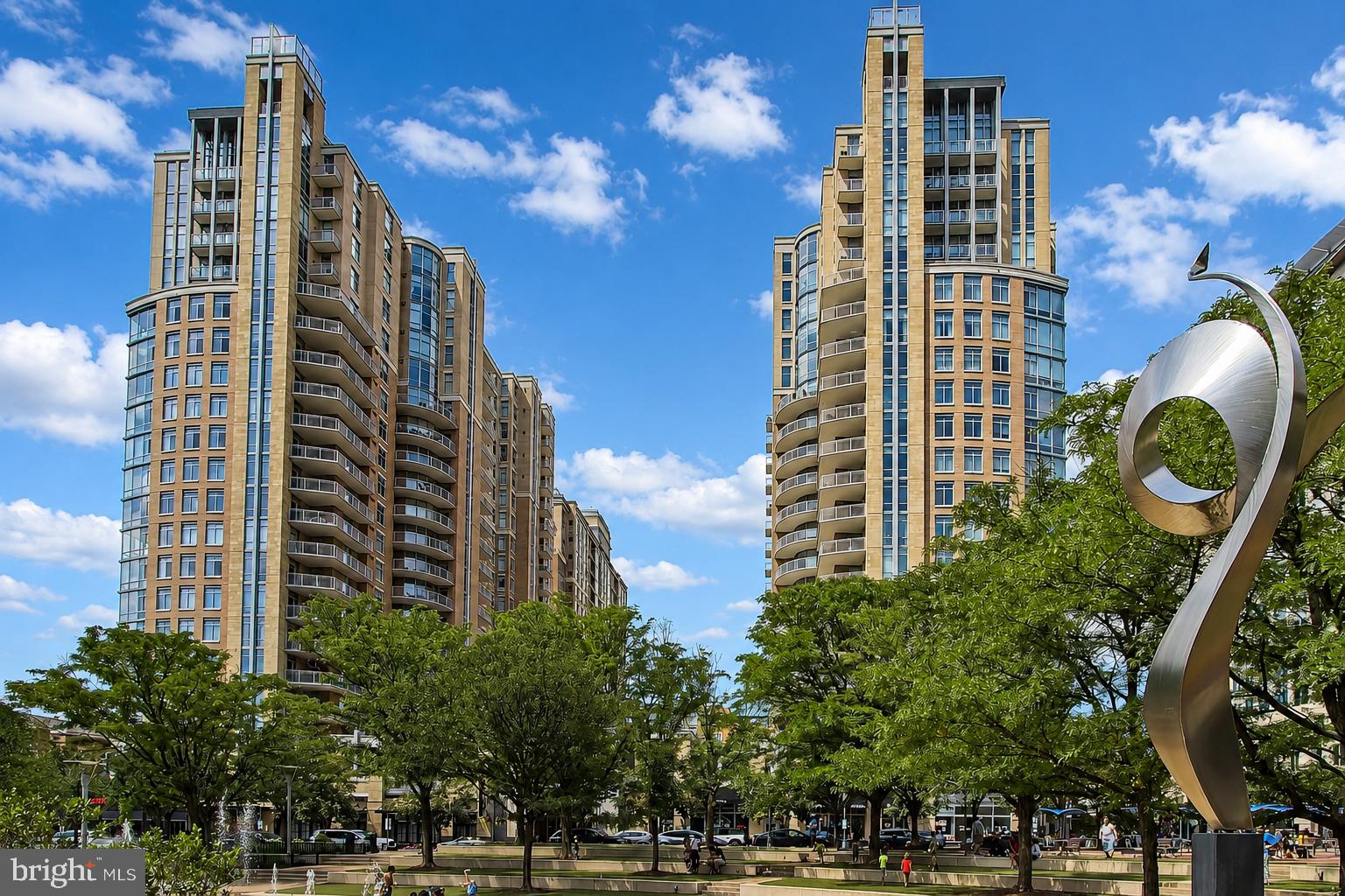 This exceptional condo offers all the amenities you are looking for in an amazing, sought-after location in one of Northern Virginia’s most coveted locations.  Enjoy panoramic skyline views from floor-to-ceiling windows and glass doors!  The private balcony is the ideal place to sip your morning coffee or toast your evening glass of wine.  Upon entry you will be amazed by the large open spaces inside, offering many different options. The attached builder's floorplan gives another idea, but it's yours to decide.  Step into the beautifully appointed kitchen that blends style and functionality.  Gleaming stainless steel appliances complement rich granite countertops, creating an elegant and practical workspace.  The 42" cabinetry provides abundant storage and the two cabinets with glass fronts include interior lighting to show off those special pieces.  The volcanic tile back splash also covers the base of the bar area that is lit by pendants.  The table area offers a beautiful western view – very special in fall colors – and a floor-to-ceiling window.  The glass door leads to the private balcony overlooking the vibrant Town Center with sweeping views.  Sip your coffee here in the morning and unwind with a glass of wine in the evening.  The balcony is a front row seat to the energy of Reston's Town Center.  The living room includes triple floor-to-ceiling glass windows abutting the balcony.  It's the perfect place to entertain friends or relax after a busy day.  Another large space at the entrance to the condo is very versatile, and easily can be the dining room, an office space or a den.  At the end of the day you can retreat to the primary suite designed for comfort and relaxation.  The customized walk-in closet offers abundant and thoughtful storage with built-in shelving, drawers and hanging space.  The luxurious en-suite bathroom features an expansive granite-topped double vanity, a private commode space and a separate shower and soaking tub.   The second bedroom also offers a walk-in closet and is adjacent to another full bathroom with a separate shower, a commode and a granite-topped vanity.  From the second bedroom a glass door leads to the balcony.  Two deeded garage parking spaces convey with the residence, and one of them has a difficult-to-find EV charging station.  There are electric motorized shades on all interior windows and there's an added black-out shade in the primary suite.  Life in Midtown has exceptional amenities including a resort-style swimming pool with loungers, umbrellas, tables and a life guard, a state-of-the-art fitness center, private screening room, a game room, and an elegant party and conference room with a catering kitchen.  There's lots to do here including a book club, and movie nights.  A concierge team is on hand if you need assistance.  And in the event of out-of-town visitors there are two suites where residents can book occupancy.  A property manager is on site Monday through Friday from 9 a.m. to 5 p.m. and a concierge is available 24-7.  Beyond your door Reston's Town Center offers a vibrant, walkable space with great shopping, amazing restaurants, a theatre, free concerts in summer and ice skating in winter, an amazing art center, an Apple Store and artisan ice cream shops.  Its safe to say you will love living here!