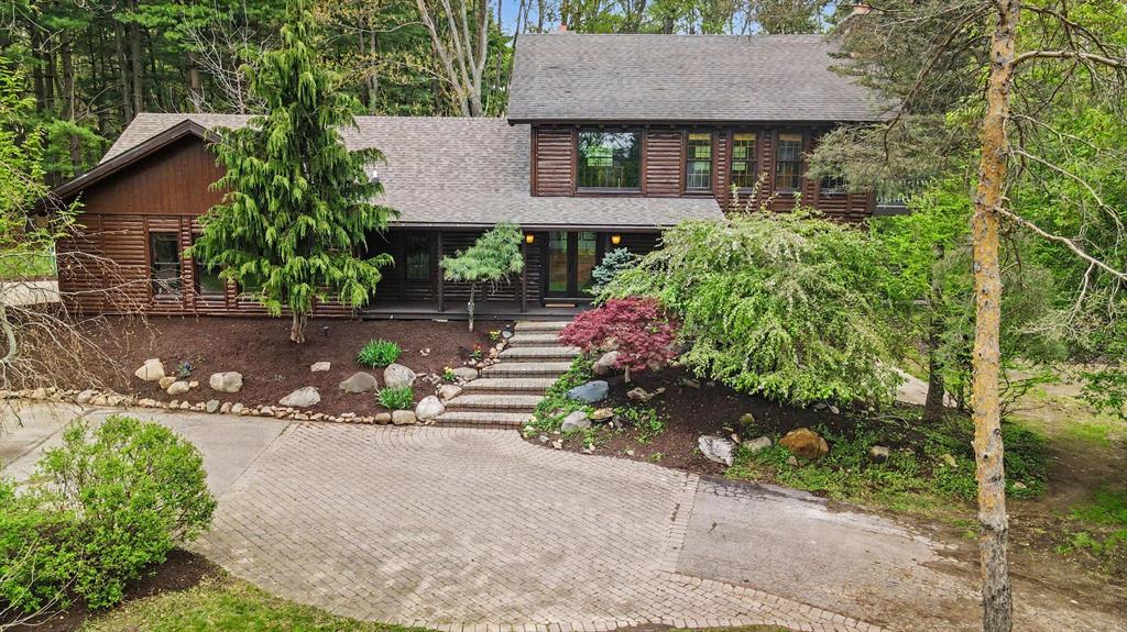 Tucked away on 1.83 wooded acres along the meandering banks of Honey Creek, this one-of-a-kind log cabin-inspired retreat offers the perfect blend of rustic charm, modern updates, and peaceful natural surroundings - all just minutes from the heart of Ann Arbor. Lovingly maintained and thoughtfully updated by the same family for more than 30 years, this special property is ready to welcome its next chapter. A circular drive and dual carports create a warm first impression, while the covered front porch invites you inside to a home filled with character and flexibility. On the west side of the home, a former attached garage has been transformed into an expansive open-concept living space featuring a chef's kitchen, dining area, and spacious living room beneath a vaulted ceiling with skylights. The beautifully updated kitchen offers granite countertops, abundant cabinetry and display storage, professional-grade stainless steel appliances (including a wine fridge), and an island workspacewith breakfast bar, while the living room is anchored by warm wood floors and an impressive stone feature wall ready for your built-in television. The main level includes three bedrooms, two full bathrooms, a powder room, and convenient bedroom-level laundry. The serene primary suite is a true retreat with two closets, a wall of windows, private balcony overlooking Honey Creek, and a spa-inspired remodeled bath complete with soaking tub, rain shower, and unique vanity with ample storage. Two additional bedrooms share a Jack-and-Jill bath, including one with a charming loft space kids will adore. Upstairs, a versatile second-floor living area offers endless possibilities. Currently configured as a spacious family room with a stone fireplace and secondary kitchen area, this flexible space could easily become the ultimate game room, guest suite, in-law apartment, or teen retreat. Step outside to yet another private balcony with tranquil creek and woodland views. The finished lower level expands the home's functionality with an additiona