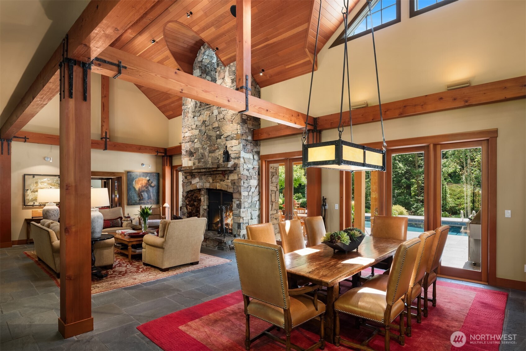 Open living and dining area with stone fireplace and timber beams