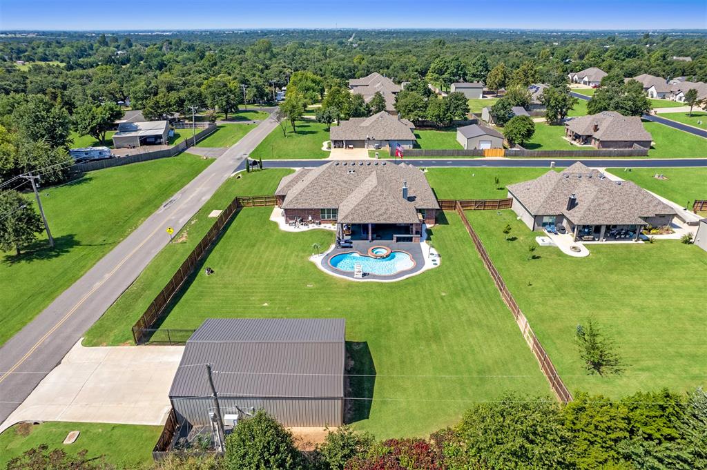 Unbelievable home in the Edmond School District on a spacious .82 acre lot complete with a sparkling pool and hot tub! This beautifully maintained home is packed with upgrades, including full sprinklers front and back, security cameras with 4K audio/video inside and out, professional landscaping with curbing, and full guttering. Permanent LED holiday lighting & eave lighting with timers make this home shine year-round. The inviting front porch features stamped and stained concrete that adds charm before you even step inside. Through the front door, a designated foyer opens into a light-filled, open-concept great room with expansive windows. A striking red brick gas fireplace with a dark wood mantle extends to the ceiling, while durable wood-look tile flows throughout the main living spaces. The kitchen is a showstopper with granite counters, double ovens, a built-in gas range, farmhouse stainless steel sink, walk-in pantry, and an additional prep island. A large counter-height island with seating connects seamlessly to the living area, and the dining space easily fits a full-size table. The primary suite is generously sized with oversized windows bringing in natural light. The ensuite is thoughtfully designed with heated floors, double vanities, a walk-in tiled shower, and a massive closet. Nearby, the laundry room includes space for a full fridge/freezer. Up front, a versatile bonus room sits next to a full bath perfect for guests. The opposite wing of the home features 3 more bedrooms: 1 with a private ensuite and walk-in closet, and 2 that share a hall bath. The backyard is a true oasis! Enjoy a fully equipped outdoor kitchen with gas grill, gas fireplace, mood lighting, & extended patio space around the pool. A 30x40 shop delivers with mini-split heat & air, full insulation with &#189;-inch plywood walls, shelving and cabinets, LED lighting with ambient sensors, 200-amp service with both 110v and 220v power & its own private drive access off Charter Oak.