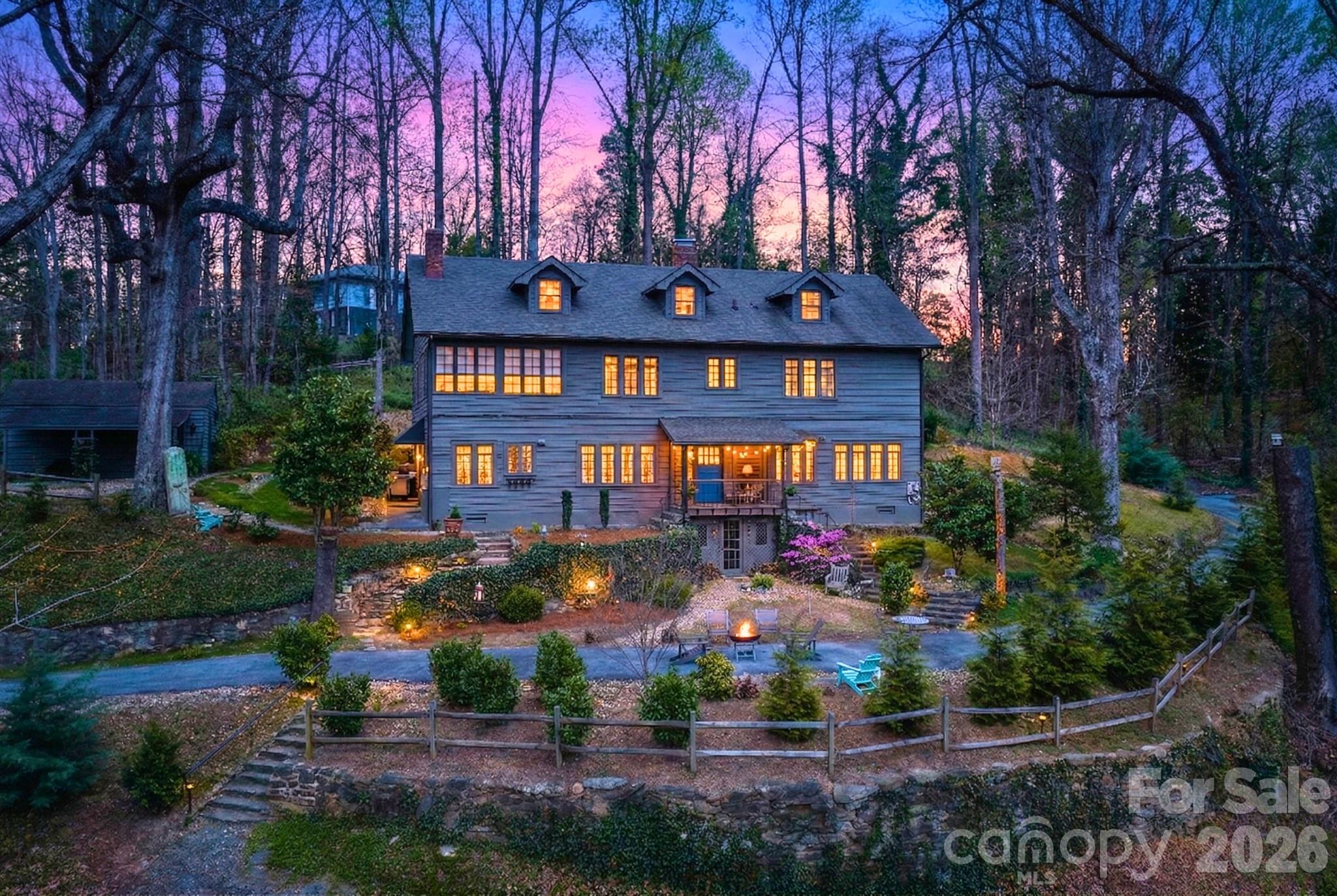 Historic “Mostly Hall” sits just steps from the heart of Tryon, offering a rare combination of walkable convenience, privacy, and enduring architectural significance. Originally built circa 1912, this landmark residence reflects the charm of an English cottage with Cape Cod influences, now thoughtfully reimagined for modern living.Set on over an acre of mature landscaping with stone walls and winding garden paths, the home feels tucked away and serene, yet remains moments from Tryon’s shops, restaurants, and cultural scene.Inside, the home has been carefully updated while preserving the craftsmanship that defines its character. Wide archways, exposed beams, rich hardwood floors, and original millwork create a sense of warmth and continuity throughout. Natural light pours through classic Craftsman-style windows, highlighting details like beadboard, crown molding, brick accents, and custom built-ins.The main living spaces flow effortlessly, anchored by a charming brick fireplace and extending into a gracious dining room ideal for gatherings. A sweeping staircase adds architectural presence, leading to well-appointed upper levels.The kitchen blends timeless design with modern function, featuring Carrara marble countertops, custom cabinetry, gas range, and stainless appliances, complemented by exposed brick and open shelving.Upstairs, three bedrooms and three baths include a spacious primary suite with sitting area, along with a sleeping porch and dedicated laundry.A standout feature is the private, fully equipped guest suite with its own entrance. Complete with kitchenette, living area, bedroom, and full bath, it offers exceptional flexibility as a guest retreat, extended living quarters, or income-producing opportunity.Fully updated, walkable to town, and steeped in Tryon history, this is a rare chance to own a property that offers both lifestyle and long-term value.