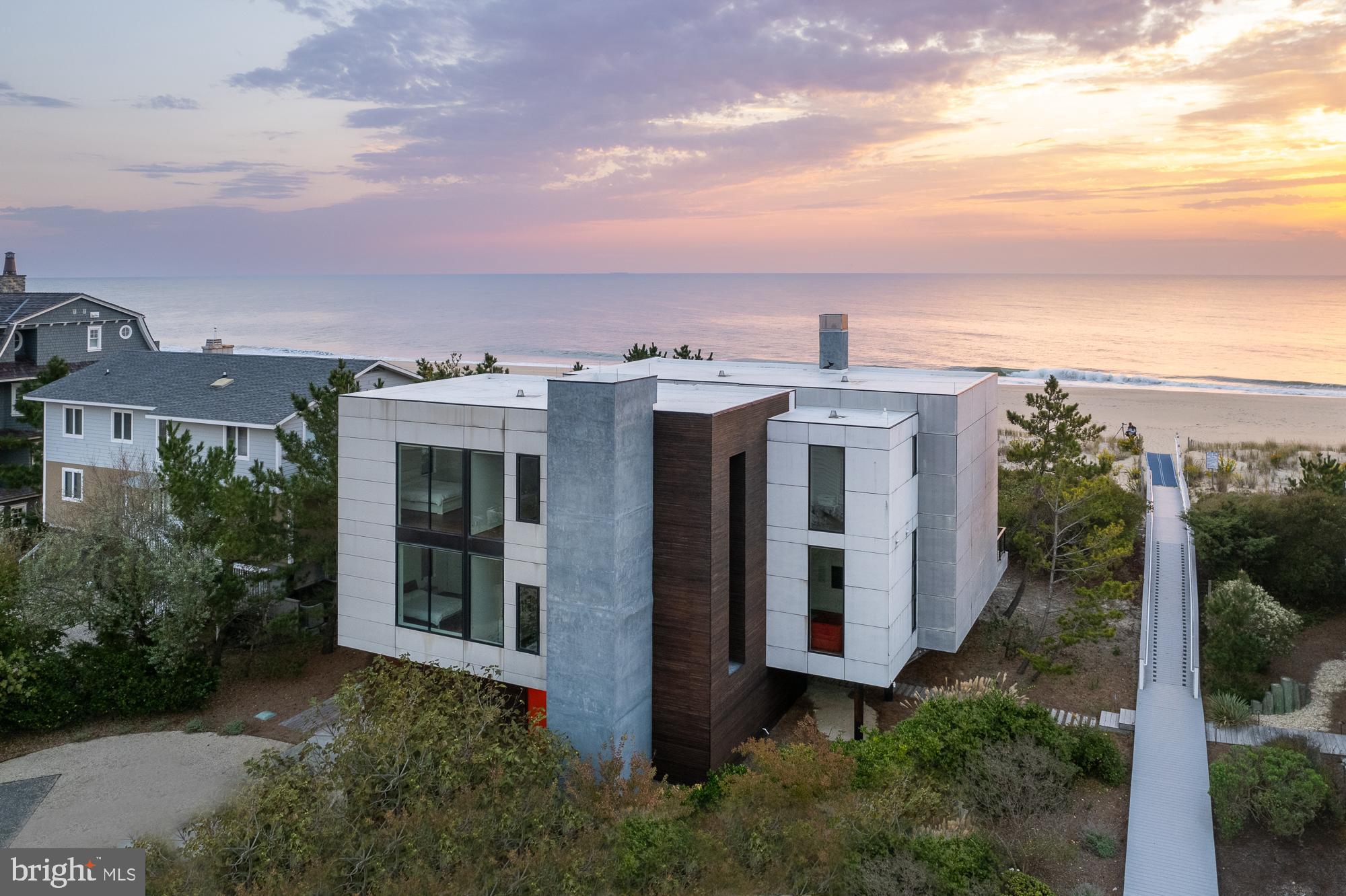 Introducing a modern architectural marvel, nestled within serene North Bethany Beach dunes, masterfully designed by the acclaimed architect Robert Gurney, FAIA. This residence effortlessly blends innovative design with the natural beauty of its surroundings. The property boasts six bedrooms plus a den, three full bathrooms, and a half bathroom, offering ample space for contemporary beachfront living.The minimalist aesthetic of the home is both intentional and striking. The exterior features a harmonious blend of fiber cement board, stucco, and wood, while the interior is finished with reclaimed walnut flooring and crisp white painted millwork. The detailing throughout is meticulously executed, creating a sense of refined simplicity that perfectly complements the expansive views of the Atlantic Ocean.The kitchen is a chef's dream, outfitted with flat panel white cabinets and state-of-the-art Miele appliances, including a built-in coffee machine for your morning brew. The fixtures throughout the home are of the highest quality, featuring Hans Grohe and Graff Designs, ensuring every touchpoint is a luxurious experience.Designed to hover gracefully above the dunes, the home offers unobstructed views of the Atlantic, allowing you to fully immerse yourself in the tranquil surroundings. Wood slats on the south side and lower levels invite gentle sea breezes into the home, while the innovative design of the west-facing stairwell allows light to filter through without overwhelming the space with harsh sunlight. The home was constructed using twenty-two existing pilings with the addition of eight new, in order to expand the building envelope all while maintaining the DNREC requirements. A marvel which cannot be constructed by today's standards and regulations.This property is more than just a home; it’s a sensory experience where the seamless interaction between indoor and outdoor living takes center stage. A rare opportunity to own a residence that is as much a work of art as it is a sanctuary, offering unparalleled ocean views, sophisticated design, and a deep connection to the natural environment.