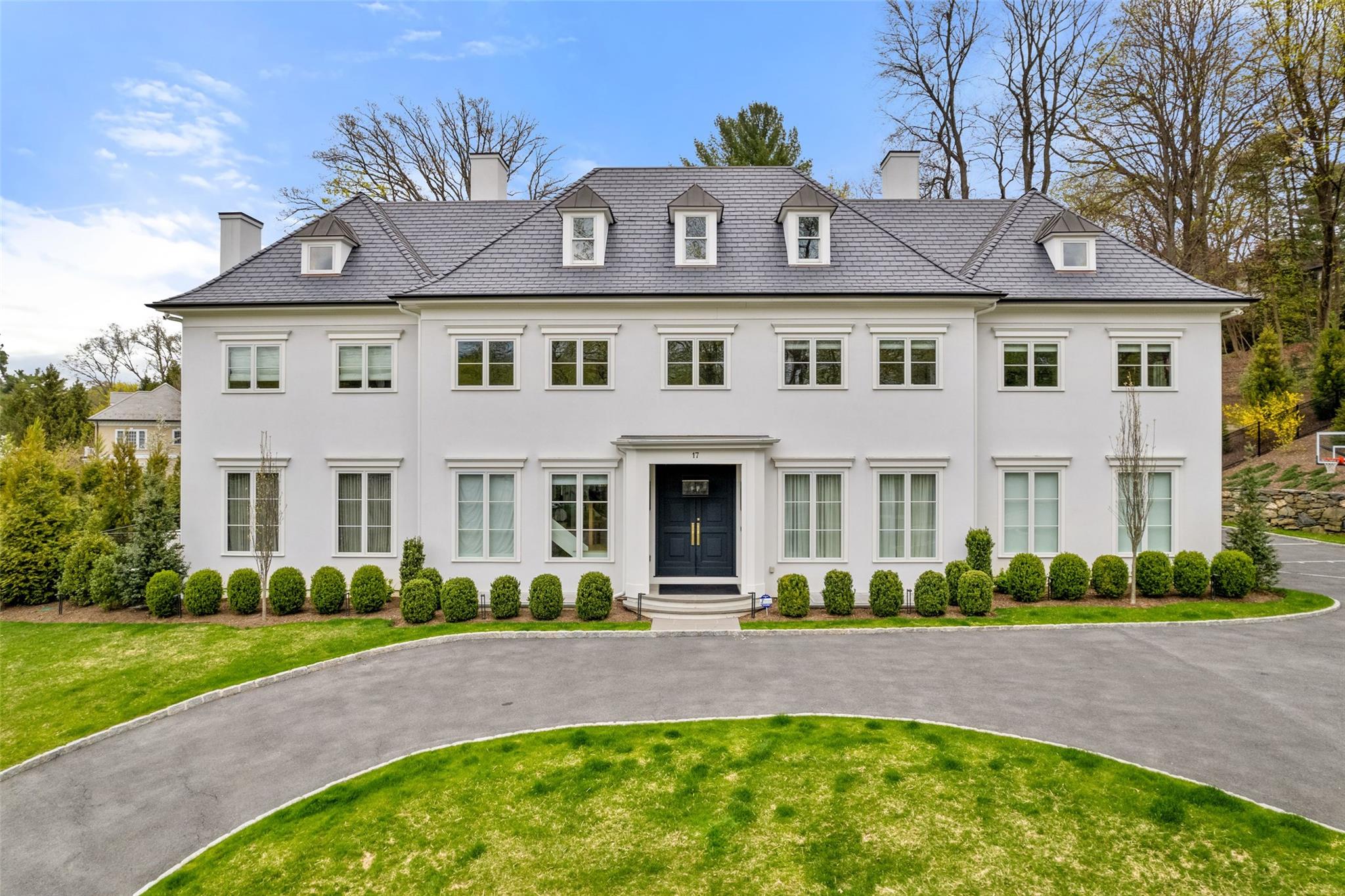 Achieve a new level of luxury living in this showplace featuring meticulously curated interiors and over an acre of resort-like outdoor space in Scarsdale's sought-after Grange estate section. Custom-built in 2021 and thoughtfully upgraded, the sprawling sanctuary boasts over 9000 square feet, soaring ceilings, swaths of premium hand selected marble finishes, handsome millwork and numerous other bespoke details. Three-inch-thick oak entry doors welcome you inside the double-height foyer, surrounded by a contemporary staircase and elegant picture-frame molding. Ahead, the dramatic lounge welcomes gracious gatherings with 10 feet tall ceilings. A spectacular walk-up bar serves as a centerpiece of the space featuring a black marble countertop with gold veining  and commercial-grade appliances. The adjacent glass wine room ensures your favorite vintage is always close at hand. To the right of the entry, the formal dining room invites you to plan your next lavish dinner party under coffered ceilings and a tiered chandelier. A powder room with a bold floating marble vanity and metallic wall coverings adds convenience to the thoughtful entry gallery. Curl up in the family room in front of the upgraded linear gas fireplace flanked by a marble wall and illuminated built-ins. Sheer window coverings and a wall of glass doors give the space an airy Miami ambiance. Elevate your culinary achievements in the stunning open kitchen anchored by a massive 10-foot-wide Calacatta marble waterfall island. Custom cabinetry surrounded top-of-the-line appliances. A well-stocked butler's pantry and storage pantry are perfect for large-scale entertaining while keeping the primary open kitchen neat as a pin. The home office is a magazine-worthy work-from-home destination finished with a custom white oak desk and bookshelf, a private full bathroom, and French doors that open directly to the pool deck. Dream sweetly in the serene primary suite featuring vaulted ceilings and a bespoke floor-to-ceiling tufted headboard and bench that coordinate seamlessly with the sophisticated paint palette and window coverings. Two massive walk-in closets include a boutique-inspired retreat, where a huge island is surrounded by floor-to-ceiling custom cabinetry. The spa-inspired en suite bathroom beckons with a soothing jetted soaking tub, frameless glass rain shower for two, and a double vanity, all surrounded by custom hardware, Dolomite marble herringbone floors and tile walls. There are 4 additional en suite bedrooms and a laundry room with 2 sets of washer and dryers on the second floor. Fun and games await in the lower level with 9 foot ceilings, a sprawling rec room and the cozy home theater featuring stadium seating and a cinema-quality AV system. A large gym boasts rubberized flooring, mirrored walls, glass doors and state-of-the-art equipment. Outside, 1.2 acres of manicured grounds facilitate a seamless indoor-outdoor lifestyle that feels like vacationing in your own backyard. The 20-foot by 50-foot saltwater pool/spa is wrapped with chic porcelain tile pavers. Grill masters will adore the full outdoor kitchen with a Lynx gas barbecue and refrigerator, while the cabana provides a shaded area for al fresco dining and gameday gatherings. This level backyard is illuminated with outdoor lighting and landscaped with over 200 trees and plants to create an idyllic oasis. Practice your three-point shot in the half-court basketball court while the oversized motor court and three-bay garage provide abundant off-street parking. This home's extensive upgrades include an indoor-outdoor Sonos surround sound system and a whole-house generator. Located in Greenacres' sought-after Grange estate section, this home is zoned for top-rated schools, including the newly renovated Greenacres Elementary, and nearby parkways and Metro-North trains provide easy access to New York City and beyond.