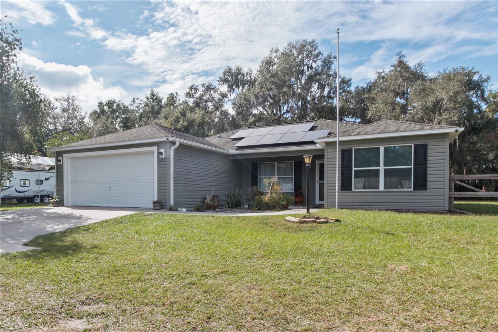 OWNED SOLAR + IMMEDIATE SAVINGS – SELLER PAID OFF SYSTEM AT CLOSING! Experience energy-efficient Florida living in this well-kept 2009 home featuring an owned 8.5 kW solar system (2023 & under warranty) valued around $40K.  Seller will pay off the solar in full, resulting in virtually no power bill beyond the standard $36/month utility service charge, plus enjoy the added value of owned solar  — immediate savings and equity for the buyer. The home offers 1,650 sq ft under A/C, including a 260 sq ft bonus room under heat and air from a reversible garage conversion. Open-concept living, dining, and kitchen areas feature vaulted ceilings and luxury vinyl plank flooring throughout, creating a spacious, modern feel with updated finishes. The living area’s 75” flat-screen TV with sound bar is included. Step outside to a 33' x 9' screened lanai, partially covered for year-round enjoyment, overlooking a fenced 0.7-acre flag lot set back from the road for a quieter, more private living environment with plenty of room for pets, play, or future additions. This property combines comfort, modern efficiency, and value — all within minutes of shopping, dining, and major roadways. Schedule your showing today and see how affordable Florida solar living can be!