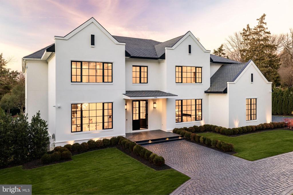 A new crown jewel in McLean, developed by Ambar, 1102 Chain Bridge Road commands attention in the prestigious Langley Farms enclave. A newly constructed triumph that fuses contemporary elegance with transitional château attributes, this estate is tailored for the digital age yet crafted with an artisanal touch seldom seen today. Spanning over 16,000 square feet, it is a showcase of forward-thinking design and enduring craftsmanship.Set on a rare 0.8-acre lot, the approach reveals a gracious cobblestone motor court enveloped by sleek, mature privacy landscaping. Beyond grand double doors, a herringbone-floored foyer offers clear sightlines through the home’s depth, introducing 12-foot ceilings, solid walnut floating stairs, and 10-foot custom wood doors with Emtek hardware. These are testaments to the home's exacting attention to detail. Wide-plank engineered floors and recessed crown uplighting provide a refined warmth throughout.Designed equally for grand entertaining and everyday comfort, the main level flows effortlessly between formal and informal spaces. At its center is an aspirational chef’s kitchen: dual waterfall islands clad in Spanish marble, Italian composite cabinetry, a vintage Viking 8-burner range, and a full Miele suite. A separate, fully enclosed spice kitchen with its own Miele appliances adds further versatility.Three floor-to-ceiling collapsible glass walls open to reveal true indoor/outdoor resort living. A covered patio offers ideal al fresco dining, while the marble terrace introduces a stunning heated lap pool with spa, waterfall, hidden drainage, and an automatic cover. A private guest suite with direct patio access and panoramic pool views is quietly tucked away on the main level.Upstairs, the primary suite is a sanctuary of serenity. Beyond a long corridor and double doors lies a generous sleeping room and private sitting area, divided by a custom linear fireplace. Two sets of French doors open to a private terrace with sweeping views. The spa-inspired bath is clad in Dekton and features radiant heated floors, eight shower heads, a Kallista soaking tub, dual water closets, and separate his-and-hers dressing rooms outfitted in custom Italian cabinetry with illuminated glass displays and center islands.Additional upper-level bedrooms are grand in scale, each with tray ceilings, custom walk-in closets, and designer en suite baths. A convertible nursery offers discreet access to the primary suite. A spacious laundry room with dual islands and full-height cabinetry completes the upper level.The lower level is designed for elevated recreation and wellness. Amenities include a professional home cinema, a full bar with a Dekton island, and a fireside lounge wrapped in Porcelanosa tile. A secure safe room with 36-inch concrete walls and a Fort Knox vault door offers peace of mind. The wellness wing is a true retreat, with a steam shower, commercial sauna, fitness studio, and walk-up access to the outdoors.Engineered for longevity and performance, the home features a commercial-grade elevator, 600-amp electrical service, copper plumbing, five Carrier HVAC zones, and dual 80-gallon water heaters. Infrastructure is in place for a full-house gas generator. A central security suite monitors the 8-camera system, while a sophisticated URC system provides integrated control of Lutron lighting and concealed surround sound via in-wall iPads and smartphones.The 54-foot four-car garage with soaring ceilings is a dream for the automobile enthusiast. Meticulous landscaping and artful hardscaping unify the estate’s bold presence with its refined aesthetic. With commanding architecture and an unrivaled array of modern amenities, 1102 Chain Bridge Road stands as one of the Capital Region’s most exceptional residential offerings.