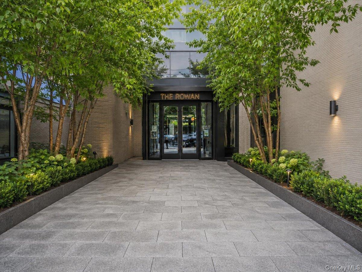 Built in 2020, The Rowan is home to this distinctive three-bedroom, two-bathroom residence, which includes a private garage parking spot and pairs a beautifully finished interior with an oversized 1,385-square-foot private terrace that substantially expands the home’s living and entertaining space.The bright, open living and dining area is defined by wide-plank white oak flooring, oversized European-style windows and custom ceiling beams with integrated recessed lighting—an owner-added detail that brings warmth and architectural interest to the space. Directly accessible from the living area, the expansive terrace offers multiple areas for outdoor dining, lounging and entertaining, surrounded by mature greenery for added privacy.The streamlined kitchen features Raw Concrete Caesarstone surfaces, a generous island, light walnut and grey lacquer cabinetry, a full-height pantry and Miele appliances, including a separate wine refrigerator.Both bathrooms are finished with carefully selected stone and tile. The primary bathroom features Pelle Grigio marble, Basalt grey stone flooring and a glass-enclosed shower, while the second bathroom combines matte ceramic wall tile, porcelain flooring and an alcove bathtub. Toto toilets and polished-chrome Dornbracht fixtures complete each space.The current owner has further enhanced the residence with custom window treatments and integrated surround-sound speakers throughout the interior and terrace. The sound system is controlled by a universal remote, with its components neatly housed in the dedicated laundry room. Central heating and air conditioning provide year-round comfort.The Rowan’s amenities include a part-time attended lobby with virtual concierge, Sensory Garden, residents’ lounge, landscaped roof terrace, fitness center, children’s playroom, soundproof music room and dog-washing station. The building is serviced by two elevators.Set in the heart of Astoria, the residence is convenient to neighborhood dining, shopping, nightlife, waterfront parks and transportation to Manhattan. With a true three-bedroom layout, substantial private outdoor space and custom enhancements rarely found in a resale, this home offers a compelling combination of comfort, design and functionality.A monthly fee applies to the parking spot.All information is deemed reliable but is not guaranteed and should be independently verified.