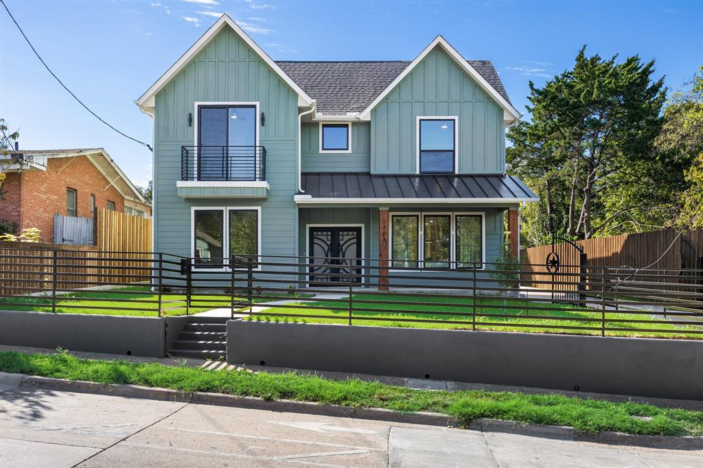 New construction in Oak Cliff, minutes from the Bishop Arts District. A covered front porch and double iron and glass doors open to white oak floors and an open staircase with black metal railing set against a slat accent wall. A built in bench with hooks and cubbies sits just inside, and a powder bath serves guests. Living, dining and kitchen flow together with windows on every side. A floor to ceiling sage herringbone tile fireplace with a cedar mantel anchors the living room. The kitchen is built for real cooking: an oversized quartz island with seating for four, brass fixtures, gold undermount sink, gas range, custom vent hood, herringbone backsplash and white shaker cabinetry. The primary suite is down, with a freestanding tub, separate shower and dual vanity. Four more bedrooms and a study nook are up, and one opens to a private balcony. Laundry down with a tankless water heater. A separate 383 square foot guest quarters with its own bath and closet sits at the back, ideal for a guest suite, home office or studio. Two car detached garage, covered patio, full wood privacy fence and new landscaping front and back. Quick access to Jefferson Blvd, I-30 and downtown Dallas.