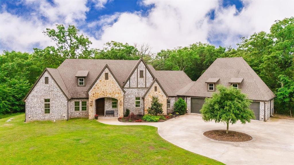 This impeccable brick-n-stone 3 bedroom, 2.5 bath, with office & 3-car garage, sits on a mostly wooded 6.46 acres with scenic water views of the front pond! After driving through the gated entrance, you are greeted by the enchanting and towering gables of this 2016-built house. Walk through the front door where there is an office with double glass doors & built-in bookcase. A wall of windows in the vaulted living room showcase the private, wooded backyard plus there is a stone, gas-log fireplace with built-ins. The elegant kitchen comes with a plethora of custom cabinets, large island w-breakfast bar, Viking appliances, granite countertops, double ovens, 8-burner gas stove, stainless farm sink, oversized walk-in pantry, Travertine backsplash, & commercial grade vent. Every base cabinet has 2 pull out drawers & one has a pull out tray organizer. Ample pantry and office. A pair of modern chandeliers add a touch of sophistication in the open dining room, with luxurious hand-scrapped wood flooring throughout the main areas. Find a spacious retreat with gas-log fireplace in the primary bedroom that includes a bay window. The ensuite bathroom has Travertine tile, marble countertops, double sinks, walk-in shower, built-in vanity area, walk-in closets, & custom cabinets for extra storage. Split from the primary bedroom are two guest bedrooms with walk-in closets & a full bath that comes with Travertine tile & marble countertops. Off the garage entrance is the laundry room with Travertine tile and plenty of storage. A conveniently located half-bathroom can be easily accessed from outside. Additional bonuses are arched doorways, single & double crown moldings, custom beams, recessed lights, exceptional floor plan, solid core interior doors, wood shutters, & large picture windows. Outside, you'll find a circle driveway that leads to the garage. With wooded acreage and front pond stocked with bass & perch, this property provides privacy & recreation with a picturesque setting!