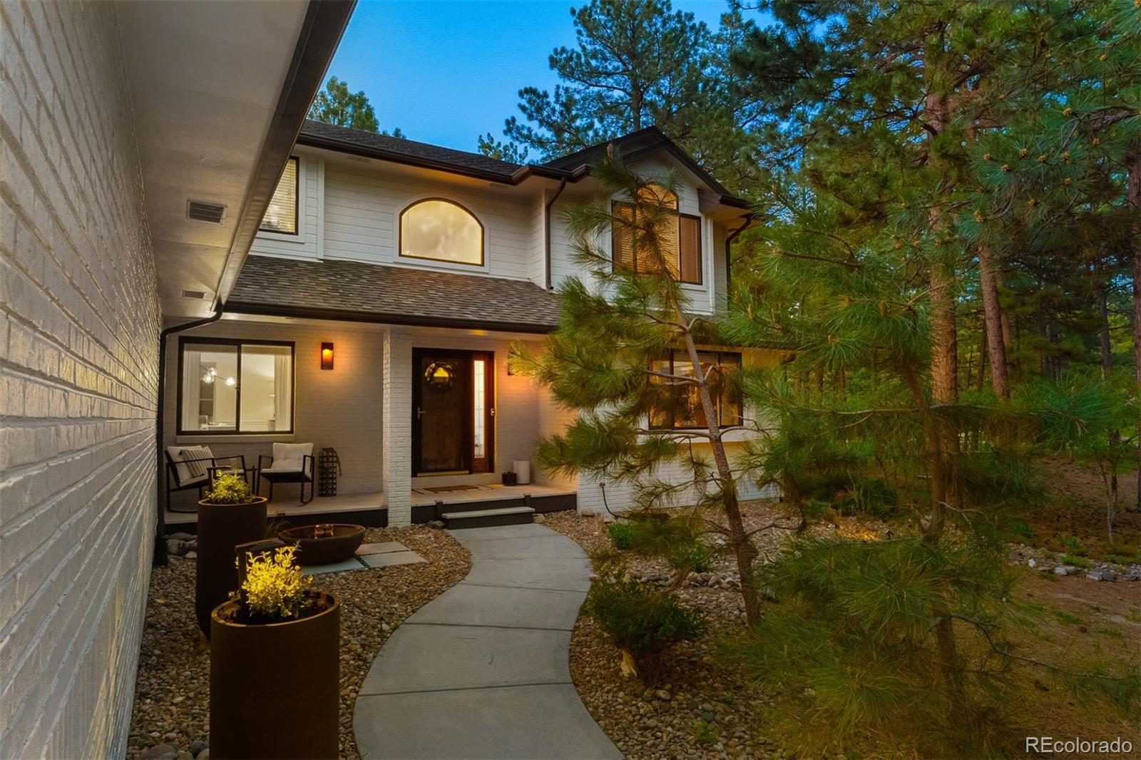 Some places feel like they’re holding their breath just for you—quiet, unhurried, wrapped in the scent of pine and the glow of Colorado sunsets. This two-acre property at the end of a cul-de-sac captures that rare stillness, surrounded by towering evergreens and the rhythms of the forest. Here, deer wander past the front porch, wild turkeys cross the drive, and the occasional bear makes an appearance—reminding you that you’re living in the heart of Colorado. 

The home is designed to meet its setting head-on, with a full-length deck, covered front porch, and walkways that draw you outside to watch the day fade into night. Inside, vaulted ceilings and walls of windows pull the outdoors in, flooding the great room and kitchen with soft, shifting light. The main level offers a guest suite with deck access, and a walk-in closet, a great room with statement fireplace, and a kitchen built for cooking and connection. Upstairs the primary retreat delivers treetop views and a feeling of calm that stays with you long after you’ve closed your eyes. 

When it’s time to gather, the finished lower level—with wet bar, recreation room, and hidden gun room—welcomes friends and family with ease. An oversized three-car garage with high ceilings and built-in storage keeps everything organized and ready for your next project or adventure. With easy access to both Denver Metro and Colorado Springs, you’re never far from what you need, but you still feel worlds away.