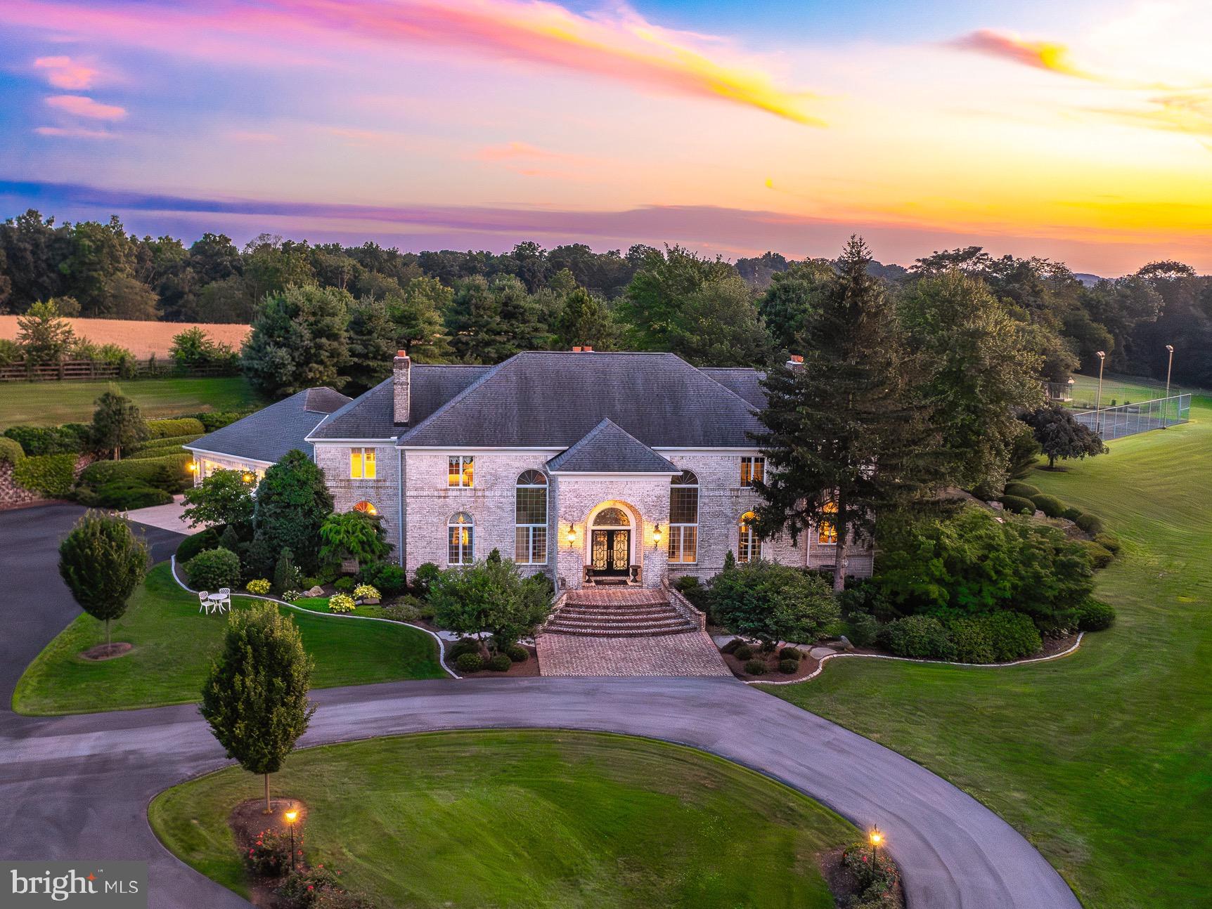 Set back along a picturesque quarter-mile tree-lined driveway, Serenity Acres unfolds across 24 rolling acres in the heart of Lancaster County, Pennsylvania, offering a lifestyle of complete privacy, effortless luxury, and endless versatility. As you approach, the grandeur of the estate slowly reveals itself—a breathtaking blend of elegance and country charm that immediately captivates. This impeccably maintained residence delivers a true resort-like experience where every detail has been thoughtfully designed to inspire comfort, function, and enjoyment. A grand, light-filled foyer welcomes you inside with custom marble mosaic flooring and twin spiral staircases, setting the tone for the sophistication found throughout. The expansive great room features soaring ceilings and a striking fireplace, while the formal dining room offers an elegant setting for entertaining, highlighted by a decorative ceiling mural and sparkling chandelier. The gourmet kitchen is a standout, equipped with premium appliances, sleek finishes, and generous prep space—perfect for home chefs or catered events alike. The first-floor primary suite is an exceptional retreat, offering a cozy fireplace sitting area, direct access to a private hot tub, and a luxury spa bath featuring a steam shower, soaking tub, heated tile floors, and heated towel holders for the ultimate in comfort. Each upstairs bedroom is a private suite with its own updated en-suite bath, providing both convenience and privacy for family and guests. The finished lower level of the home adds even more flexibility and enjoyment, featuring a second full kitchen, home theater, billiards room, fitness area, half bath, and another warm fireplace-centered living space. Step outside and you’re immediately immersed in your own private resort. The 25x100 heated saltwater pool, holding over 41,000 gallons, features a cascading waterfall and is surrounded by lush gardens (with irrigation system to keep everything looking healthy!), a stamped concrete patio, and a charming pavilion—perfect for everything from large summer gatherings to quiet morning coffees. The outdoor recreation continues with a lighted tennis court, putting green, and garden shed. For those seeking a working or hobby farm lifestyle, Serenity Acres offers over 12 acres of fenced and electrified pasture, a five-stall horse barn, and a separate steer barn with ample space. The beautifully restored 100x40 bank barn doubles as an extraordinary event venue, featuring a full caterer’s kitchen, vintage 1890s three-arched bar, state-of-the-art media and lighting systems, 2 bathrooms (one of which is handicap accessible) and seating for up to 72 guests—ideal for weddings, retreats, or private celebrations. A separate log cabin on the property serves as a charming guest or caretaker space, offering a main-level bedroom plus an open loft that easily functions as a second sleeping area. Despite its peaceful seclusion, Serenity Acres is conveniently located just 10 minutes from the PA Turnpike and Lititz, and 15 minutes to the Lancaster Airport. With unmatched flexibility for luxury living, entertaining, farming, hosting, and recreation, Serenity Acres is not just a home—it is a destination, a retreat, and a rare legacy estate where lifestyle and landscape are perfectly aligned.