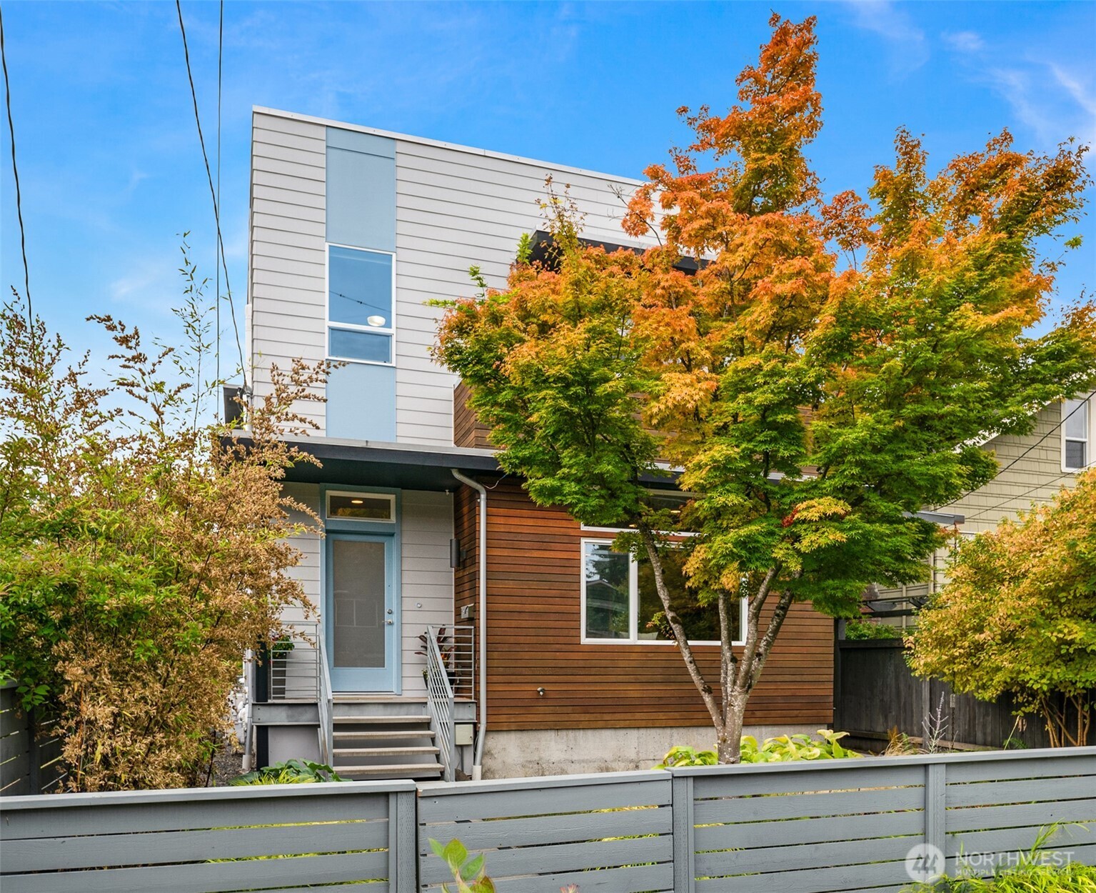 A modern North Seattle home where great design meets effortless everyday living. Thoughtfully expanded and beautifully maintained, this 2,978 SF residence pairs clean architectural lines with warm, inviting spaces and incredible natural light. Soaring ceilings and walls of windows set the tone on the open main level, where bamboo floors, custom steelwork and a gas fireplace anchor the space. The chef’s kitchen—with quartz counters, high-end appliances and plenty of room to gather—flows seamlessly to living, dining and multiple decks. Dinner parties, summer cocktails, morning coffee…there’s a spot for all of it. Upstairs, the spacious primary suite is a true retreat with spa-inspired bath, oversized walk-in closet and private deck. Enjoy four total bedrooms all on the upper level! Downstairs, the expanded lower level adds a bedroom, full bath and media room—movie night just got an upgrade. Speaking of, you can pop your popcorn and mix your cocktail at the lower level wet bar. Dangerously convenient! Heat pump for cooling, 441 SF two-car garage with EV charging, and a beautifully landscaped front rain garden round things out in the fully fenced yard. All in a fantastic North Seattle neighborhood, just blocks from coffee, restaurants and local bars, with easy access to Green Lake, Ballard, transit and commuter routes. Modern, comfortable and just plain cool.