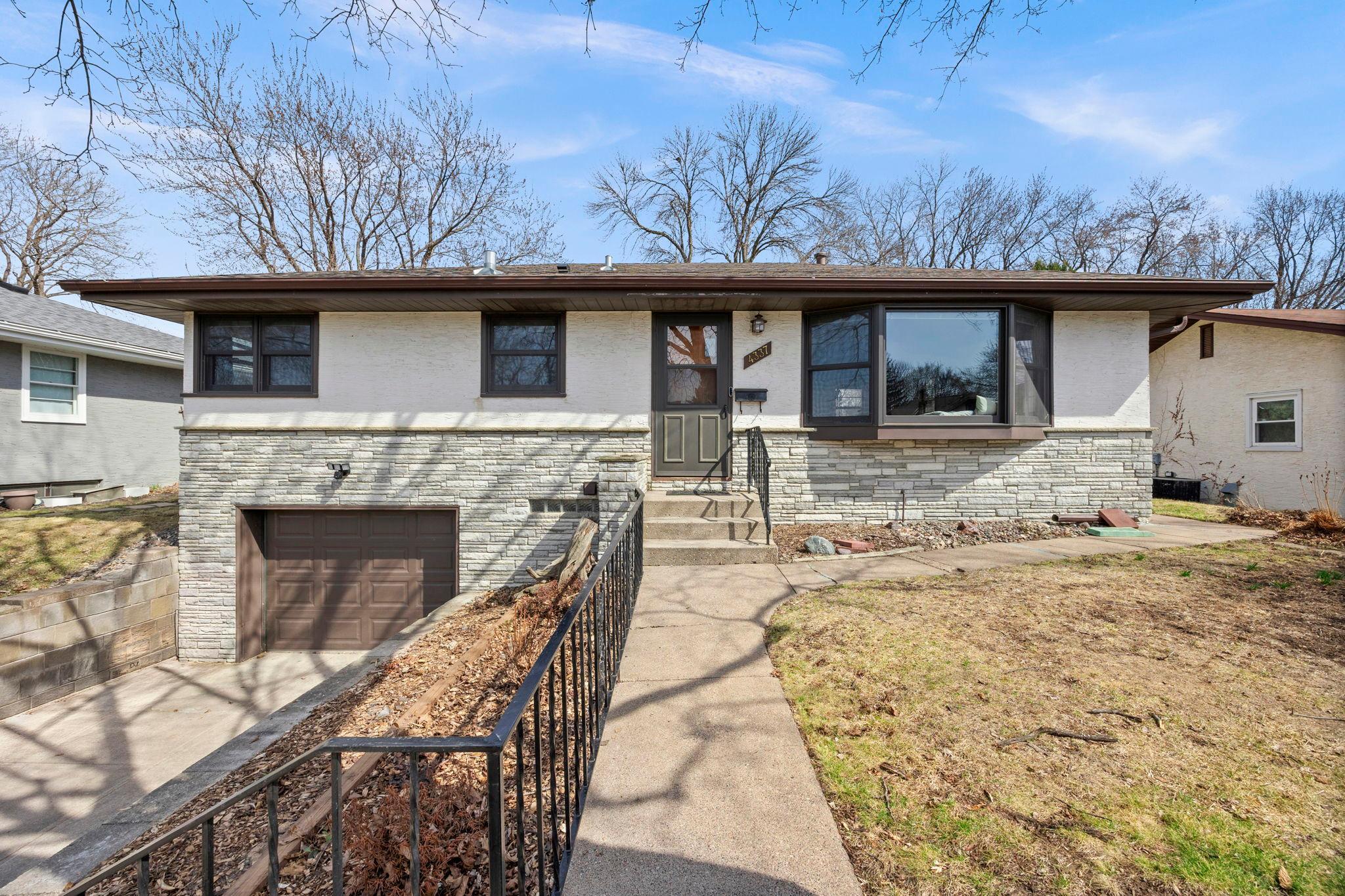 Welcoming 2-bedroom, 2-bath home with refinished hardwood floors (2020) and abundant natural light. The front-facing living room features a large bay window with cushioned bench. The kitchen offers ample cabinetry, counters, and new stainless steel appliances (2025), with access to a three-season entertaining space with bar, beverage fridge, and backyard patio with pergola. Main-level bedrooms have hardwood floors and share an updated full bath (2022). Lower level includes a family room with electric fireplace, updated ¾ bath (2025), and unfinished laundry/storage with new washer/dryer (2025) and access to the attached one-car garage. Fully fenced backyard provides a private retreat. Thoughtful updates, original charm, and versatile living spaces in a peaceful neighborhood.