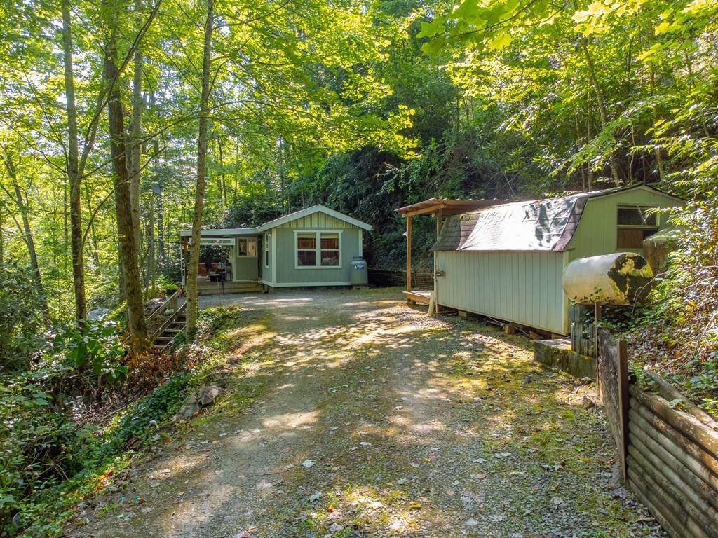 Creekside Cottage with outdoor kitchen, Wraparound Porch & Room to Grow! Tucked away in the peaceful Stecoah Valley, this 1BR/1BA cottage on 1.53 unrestricted acres delivers the perfect blend of mountain charm and outdoor living. Relax on the covered wraparound porch as a year-round creek provides a soothing natural soundtrack. Entertain with ease in the rustic outdoor kitchen, gather around the firepit, and enjoy added touches like a bunkhouse and outdoor shower—ideal for hosting guests or creating your own private retreat. Inside, the bright open floor plan features vaulted ceilings, comes fully furnished, and includes a smart sleeping nook for extra guests. The kitchen offers a gas range, ample storage, and everything needed for comfortable everyday living. Thoughtful upgrades like a tankless water heater, UV filtration system, and encapsulated crawlspace provide efficiency and peace of mind. With a 2-bedroom septic system already in place, there's excellent potential to expand. No HOA and no deed restrictions give you the freedom to use the property your way. Turnkey and ready to enjoy—just show up and start living the mountain lifestyle!