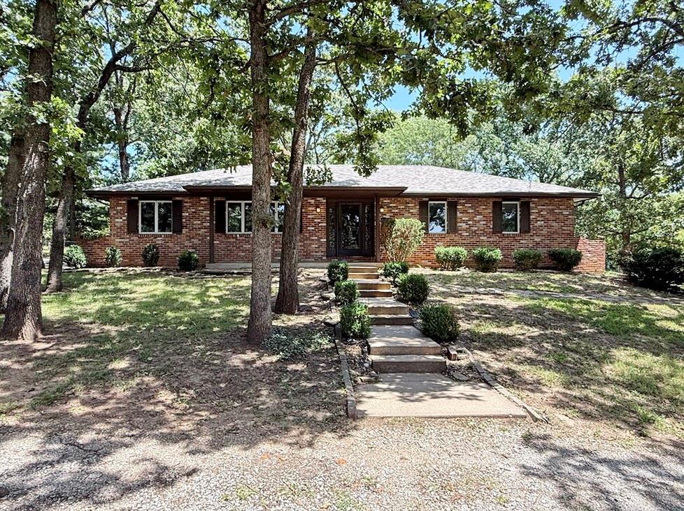 Welcome to this charming country home in a desirable rural neighborhood just outside of El Dorado Springs, MO. This well-maintained property offers the perfect balance of peaceful country living with the convenience of nearby shops, restaurants, and essential services. The brick-front exterior features a covered front porch overlooking a circle drive and shady front yard. Inside, you’ll find a spacious living room and a well-sized kitchen and dining area, connected by a beautiful see-through fireplace. The main level of this raised ranch offers 1,568 finished square feet, including three bedrooms and two bathrooms. The full basement provides an additional 648 finished square feet, featuring a second living room and half bathroom, creating flexible space for relaxing, entertaining, or hobbies. An oversized two-car garage, located in the basement, offers generous room for vehicles, equipment, and recreational gear. A covered deck off the dining room provides a private outdoor space for dining or unwinding. The property sits on a beautiful lot with mature trees and a fenced backyard, offering outdoor enjoyment while remaining close to town conveniences. This inviting home combines comfort, space, and functionality in a picturesque setting—don’t miss the chance to make this Cedar County Missouri property yours!