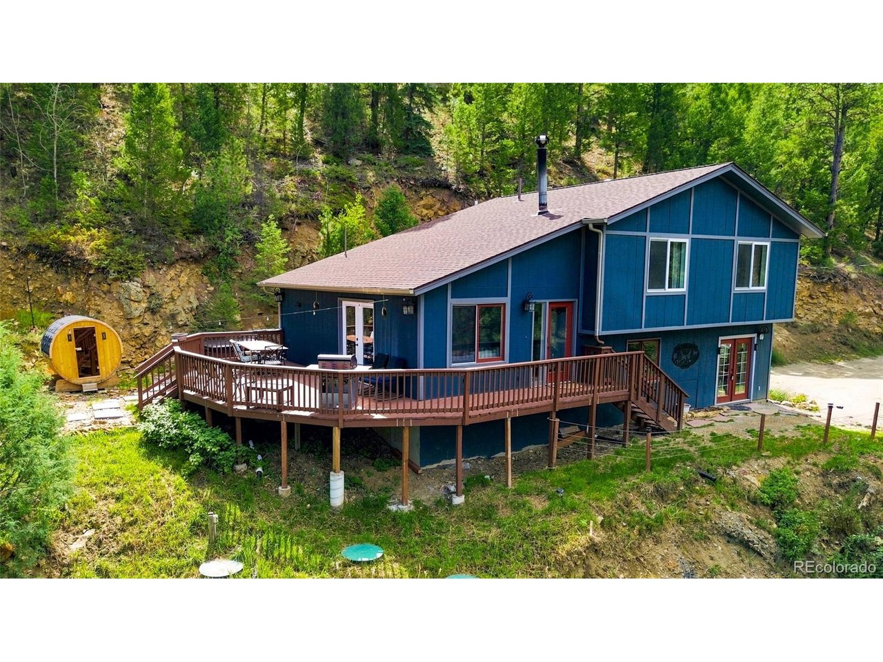 Experience Colorado mountain living at 812 Soda Creek Road, a captivating three-bedroom, three-bath retreat set on approximately 4.71 wooded acres above Idaho Springs. Sweeping mountain and forest views create a peaceful backdrop for the expansive deck and inviting outdoor living spaces.Inside, the open kitchen and living area is designed for gathering. The extensively remodeled kitchen features a generous center island, abundant cabinetry and a walk-in pantry, while a cozy wood-burning stove adds warmth and mountain character. The primary suite offers a peaceful place to recharge, and two additional bedrooms plus a spacious walk-out lower-level recreation room provide flexibility for guests, hobbies, a home office or additional sleeping space.Notable improvements include an updated septic system and water-treatment equipment, a replaced well pump and pressure tank, and newer water heater, dishwasher and laundry appliances. Outside, soak in the hot tub, unwind in the custom barrel sauna or simply enjoy the fresh mountain air and tranquil natural surroundings.Perfectly suited as either a primary residence or mountain vacation home, the property also has a history of short-term-rental use and may offer future vacation-rental income potential. Short-term-rental use is subject to Clear Creek County licensing, permit availability, regulations and buyer verification.Enjoy convenient access to historic downtown Idaho Springs, Indian Hot Springs, Clear Creek rafting, nearby hiking and mountain-biking trails, the historic Argo Mill and Tunnel, and the newly opened Mighty Argo Cable Car. The I-70 corridor also places Loveland Ski Area and additional mountain recreation within easy reach for a day on the slopes. Whether envisioned as a full-time home, personal retreat or potential income-producing getaway, this versatile property offers exceptional scenery, flexible living space and an authentic Colorado mountain lifestyle.