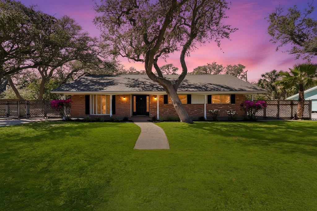 LITTLE BAY SHORES GEM! Welcome to this immaculate 3-bedroom, 2-bath brick beauty with a dedicated office, tucked into the highly desirable Little Bay Shores neighborhood. Sitting pretty on an oversized third-acre lot, the property is shaded by gorgeous mature oak trees that provide both charm and a little extra Texas sun protection. Inside, the flexible layout offers formal living and dining spaces that can easily pull double duty as a home office, playroom, hobby space, or whatever your lifestyle calls for. The cozy den, complete with a classic brick fireplace, opens to the kitchen and main living areas—perfect for everyday living, entertaining friends, or simply relaxing after a long day. Recent updates mean much of the work is already done for you: fresh interior paint, new landscaping, new carpet, new granite bathroom countertops, tile flooring in the kitchen and baths, and a resurfaced primary shower. The split-bedroom layout provides privacy for the primary suite, while thoughtful extras include a sprinkler system, partial hurricane shutters, a bonus utility/storage room, and a large rear-entry two-car garage with a fully fenced and gated driveway. Out back, the spacious yard and large concrete patio are ready for backyard barbecues, boat & RV parking, or finally hosting that gathering you've been talking about. And the cherry on top? You're just blocks from the bay, with easy access to water, local restaurants, shops, and everything that makes Rockport living so special!