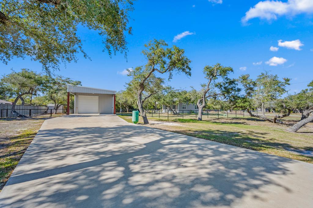 Tucked away on the beautiful Lamar Peninsula, this exceptional coastal retreat sits on just under half an acre beneath a stunning canopy of mature coastal live oak trees. Surrounded by nature and wide-open skies, the setting offers a rare blend of privacy, functionality, and relaxed coastal living.    The main residence is a thoughtfully designed barndominium, featuring two bedrooms and one full bath, soaring ceilings, an open-concept floor plan, and abundant natural light throughout. The space feels airy and inviting—perfect for unwinding after a day on the water or in the field.    The boat barn of your dreams provides ample room for boats, gear, and all your coastal toys, along with generous additional parking. The barn also includes a loft ideal for bonus living or flex space, plus a convenient half bath—making it perfect for guests, hobbies, or extra storage. It is finished out with a split-unit for AC & Heat.   Outdoors, enjoy a fully fenced yard with a cozy fire pit, ideal for evenings under the stars. A spacious covered porch invites you to cook, relax, and take in the sights of hummingbirds during migration, deer strolling through the neighborhood, and the unmistakable sound of whooping cranes flying overhead in the winter months.    Just a short drive over the bridge puts you close to everything Rockport has to offer, while still feeling worlds away. Located near world-class hunting and fishing, this property is a dream setup for nature lovers, anglers, and sportsmen seeking a peaceful coastal base camp with character and charm or full time living.
