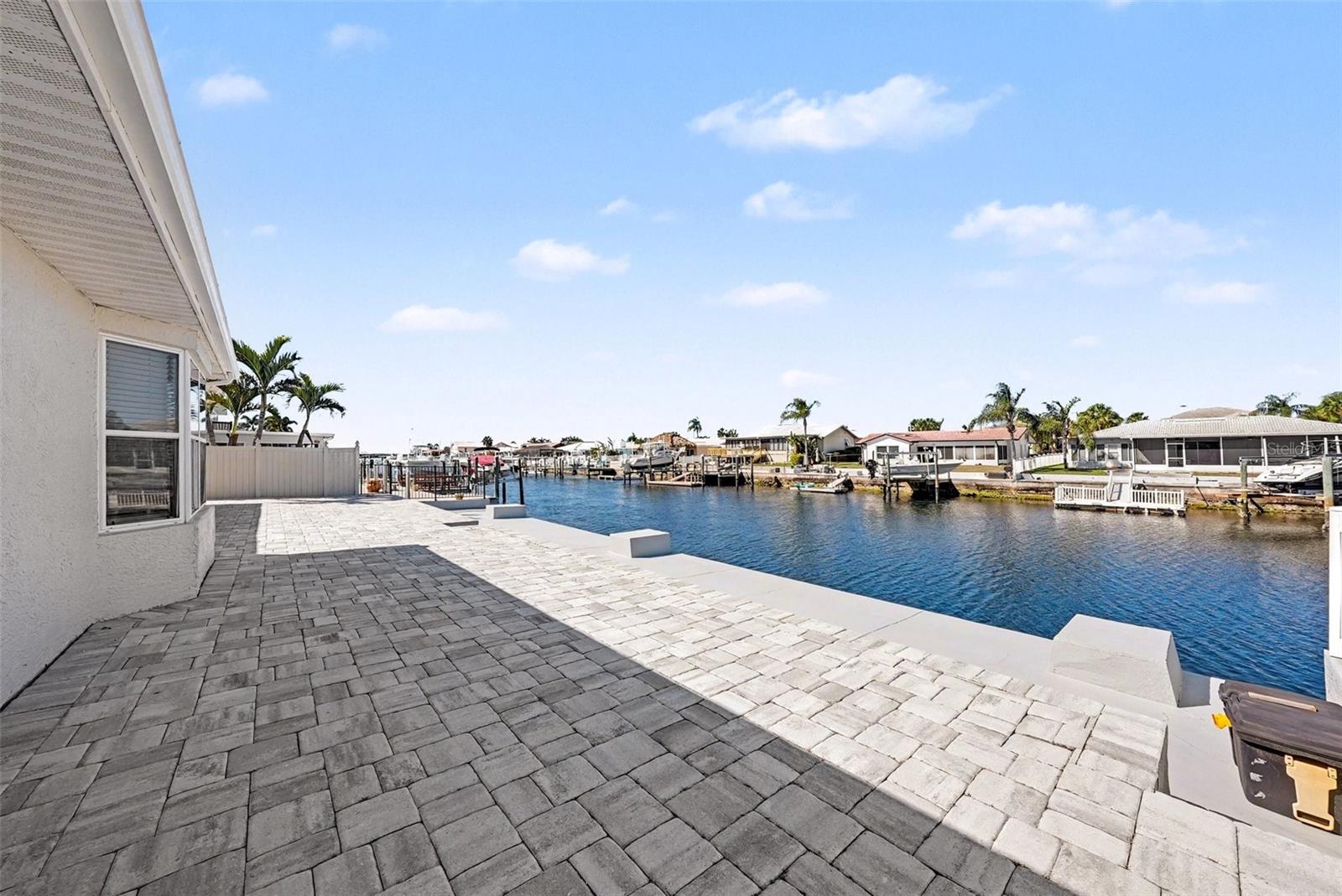 Discover the best of Florida waterfront living in Gulf Harbors in New Port Richey, where style, comfort, and quick Gulf access create an exceptional coastal retreat. This vibrant waterfront retreat delivers 67 feet of canal frontage and puts you less than a quarter mile from the open Gulf of Mexico, meaning sunset cruises, fishing trips, and waterfront dining are just minutes from your backyard. Bring the boat, the paddleboards, and your sense of adventure. Step inside and feel the energy of soaring vaulted ceilings with exposed beams, sun-filled living spaces, and stylish new luxury vinyl plank flooring throughout. The beautifully redesigned kitchen steals the spotlight with sleek stainless-steel appliances, a wine fridge ready for entertaining, a statement vent hood, and a modern drawer microwave built seamlessly into the island - perfect for hosting friends after a day on the water. Walls of sliding glass doors frame sparkling canal views, while the bay window breakfast nook is your front-row seat for morning coffee and the occasional dolphin sighting. The split floor plan keeps things comfortable and private, with a spacious primary suite that feels like a personal spa retreat, complete with dual vanities, a rain-head walk-in shower with built-in bench, and a generous walk-in closet. Guests will love having their own space too, with a private ensuite in the second bedroom and an additional full bath for added convenience. Outside is where the Florida lifestyle truly shines. A refreshed exterior, repainted tile roof and driveway, and a new paver patio create the perfect setting for sunset gatherings, weekend barbecues, or simply unwinding by the water. Located in a golf-cart-friendly community with optional access to the private beach club and neighborhood events through the civic association (a voluntary HOA), this home offers the fun, freedom, and waterfront living buyers dream about.
