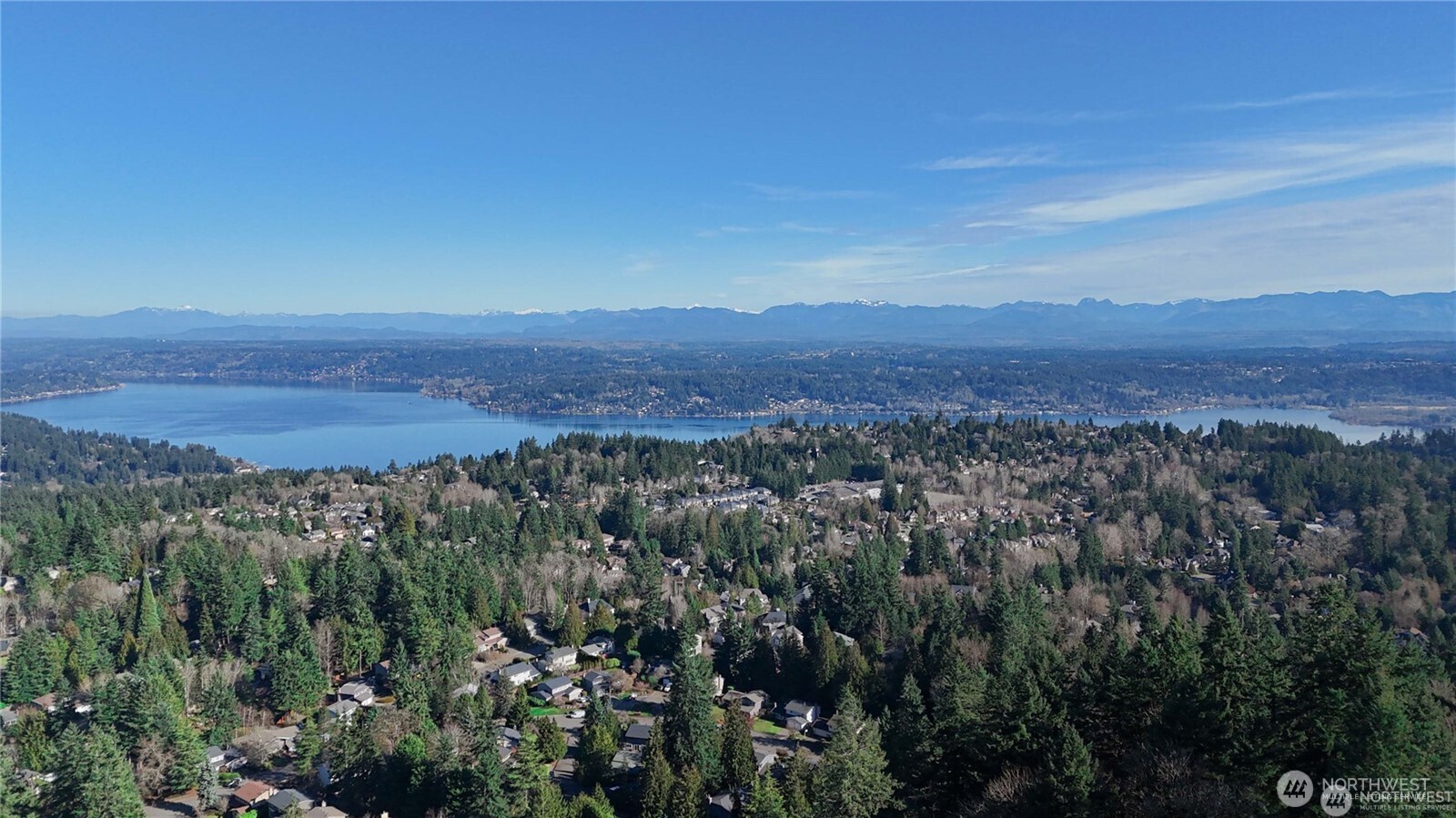 Wake up each morning to breathtaking panoramic views of Lake Sammamish and the surrounding mountains—an everyday reminder of the beauty of Pacific Northwest living. Perched on a quiet east-facing hillside cul-de-sac, this extraordinary residence captures sweeping lake, forest, and mountain vistas from expansive walls of windows that fill the home with natural light. Completely reimagined with a fully permitted down-to-the-studs remodel, every detail has been thoughtfully upgraded—from a 40-year roof, plumbing, electrical, HVAC, insulation, windows, and drywall to all-new designer interior finishes throughout. Designed for everyday comfort, the expansive layout features 5 spacious bedrooms, each with its own ensuite bath. Two main-level kitchens offer exceptional functionality—a fully equipped Western chef’s kitchen alongside a separate Wok kitchen ideal for elevated culinary experiences. Vaulted ceilings and skylights create an airy, light-filled atmosphere, while the walk-out daylight basement with wet bar provides the perfect setting for hosting guests. Step outside to a professionally designed yard featuring a private putting green, multiple entertaining patios, and a large covered deck where you can unwind while taking in the stunning lake and mountain views.Located within the top-rated Bellevue School District and highly sought-after Newport High, this is a rare opportunity to own a truly special home where luxury, privacy, and natural beauty come together.