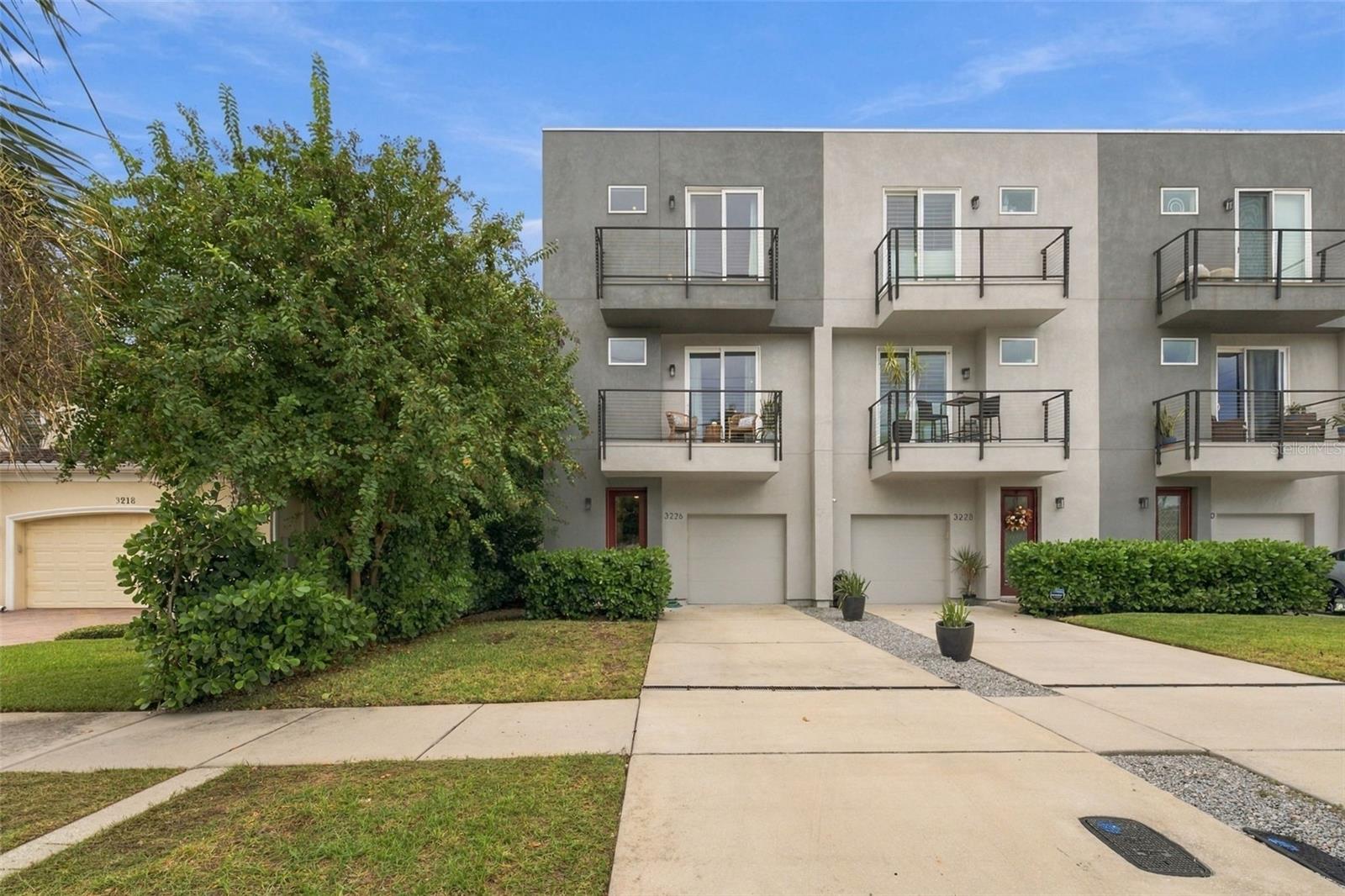 Location, Location, Location! This modern end-unit townhome puts you in the heart of it all, just minutes from Downtown Tampa, SoHo, the University of Tampa, and some of the city’s best restaurants and entertainment. Perfect for buyers seeking a low-maintenance lifestyle without sacrificing space, style, or convenience, this home offers high ceilings, wood-look tile, and fantastic storage throughout all three levels.  The first floor begins with an extended, air-conditioned garage, providing valuable extra space that could easily double as a home gym. Just inside, a large coat closet creates the perfect drop zone near the entry. Down the hall, a spacious guest suite features two closets and a full bathroom, offering incredible flexibility as a third bedroom, home office, or entertaining lounge. Sliding glass doors open directly to the outdoor patio and fenced backyard—and as the ONLY home in the quadplex with a private fenced backyard, this is a feature you won’t want to overlook! Artificial turf keeps the space attractive while making lawn maintenance a breeze. Upstairs, the second level was designed for gathering and entertaining. The open-concept kitchen, dining, and living areas flow seamlessly together, with plenty of room for a dining table, seating at the island, and a comfortable gathering space for watching the game or relaxing with friends. The kitchen features wood cabinetry, stone countertops, and stainless-steel appliances. In the living room, a Venetian plaster feature wall creates a beautiful focal point, while sliding glass doors open to a private balcony. A conveniently located half bath completes this level.  Retreat to the third floor, where you’ll find an expansive primary suite with plenty of room for a king-size bed, additional furniture, and even a cozy reading or sitting area. A large walk-in closet provides generous storage, while the primary bath features a walk-in shower and dual-sink vanity. The laundry is conveniently located between the primary suite and an additional bedroom, which also includes its own full bathroom and walk-in closet.  Additional highlights include the home’s desirable X flood zone designation, where flood insurance is not typically required by lenders, and zoning for highly sought-after Mitchell Elementary, Wilson Middle, and Plant High School. With its incredible location, flexible living spaces, private backyard, and low-maintenance lifestyle, this townhome offers a rare combination of convenience and comfort in the heart of Tampa.