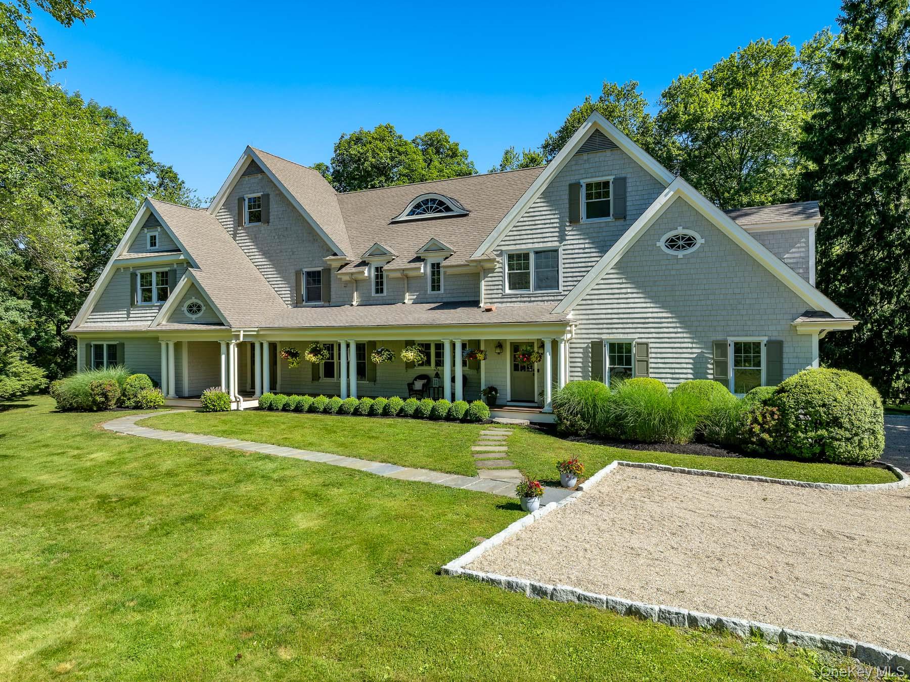 Welcome to 6 Megan Lane, a beautiful cedar shingle Colonial set on a quiet, tree-lined street in the heart of Armonk. Offering four bedrooms, three full baths, and two powder rooms, this exceptional home is perfectly suited for both everyday living and entertaining.An inviting front porch welcomes you inside, where a thoughtfully designed floor plan creates effortless flow throughout the main level. The spacious eat-in kitchen opens to the family room and connects seamlessly to the dining room, living room, and large home office. A generous mudroom with its own side entrance features a powder room and secondary staircase, providing both convenience and functionality.Upstairs, the primary suite serves as a true retreat, complete with a sitting area, two walk-in closets, and a spacious en-suite bath. Three additional generously sized bedrooms complete the second level, including one with an en-suite bath and two that share a hall bath.Both the unfinished bonus room above the garage and the basement present excellent opportunities to create additional living, recreation, fitness, or storage space tailored to your needs.Privately set back from the street on a flat, beautifully landscaped property, the home features a sprawling backyard ideal for entertaining, play, or quiet enjoyment. Combining privacy, comfort, and convenience, this special offering is located just moments from downtown Armonk, parks and schools.