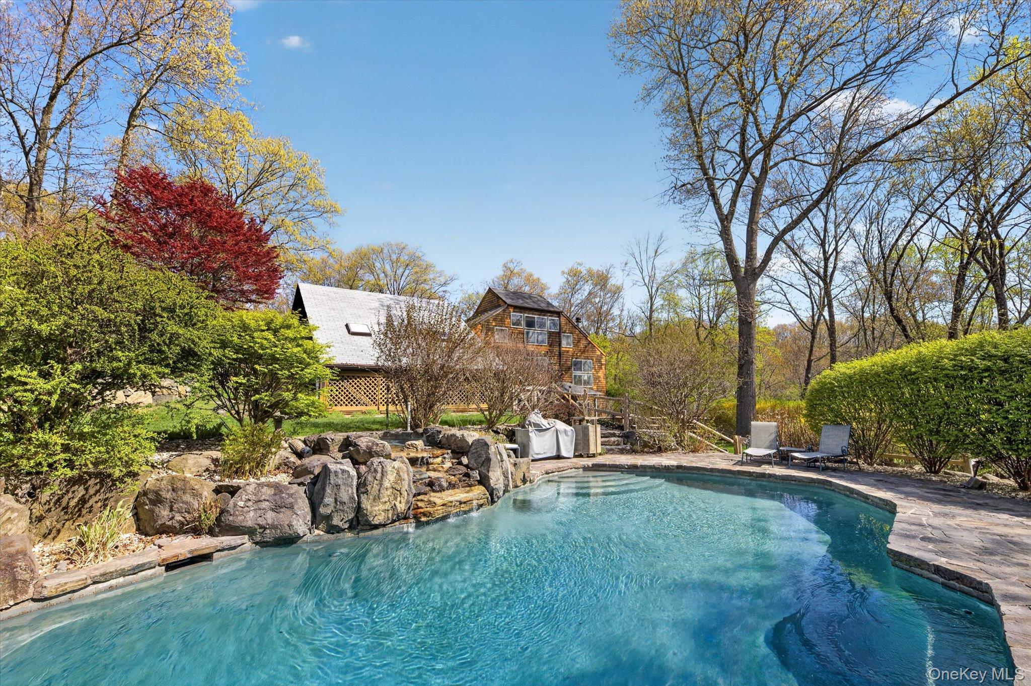 Tucked away on a quiet lane in North Salem, this one-of-a-kind contemporary home offers a rare blend of privacy, design, and natural beauty.  Set amidst a breathtaking perennial garden with meandering paths, the property invites you into a serene, zen-like retreat complete with a tranquil pool and hot tub.  Inside the approximately 2,900 square foot residence showcases an open, airy floor plan highlighted by abundant natural light, numerous skylights, and two fireplaces that anchor the living and dining spaces.  The kitchen flows seamlessly onto an inviting deck-perfect for morning coffee or effortless outdoor entertaining.  The home features four bedrooms and two-and-a-half baths, including thoughtfully designed details such as Japanese toilets.  An upper-level space provides flexibility for a home office or yoga room, adding to the home's versatility.  The grounds are equally captivating, with cleared areas ideal for vegetable gardening-where abundant harvests have thrived. The architecture evokes a timeless, Frank Lloyd Wright inspired aesthetic, harmonizing beautifully with the surrounding landscape.  Located just 55 miles north of New York City, this property offers convenient access to trains and major highways, making it ideal for both full-time living and weekend escapes.  North Salem's renowned equestrian culture and expansive open spaces further enhance the appeal of this exceptional offering.  A truly special and well maintained hidden gem - this home is where nature, design, and lifestyle come together in perfect balance.