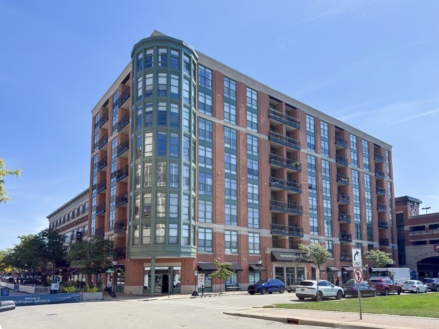 A lovingly maintained 2 bed, 2 bath corner unit at the Metropolis Place in the heart of downtown Arlington Heights. Conveniently located just steps away from the Metra, restaurants, entertainment, shopping, farmers market, Arlington Heights Memorial Library and local events; with easy access to I-90 and I-290. Experience seamless living with an open concept living room, dining room, and kitchen - the perfect floor plan for entertaining and everyday living. This corner unit boasts two stunning walls of floor-to-ceiling windows in the living room, with plantation shutters for added privacy. Enjoy beautiful sunsets and soft light throughout the day with a western and northern exposure. Recently remodeled in 2024, the kitchen features stainless steel appliances, a stainless steel apron sink, matching quartz countertops and backsplash and shaker-style cabinets. Adjacent to the kitchen is the balcony; a quaint outdoor space for grilling, container gardening, or simply enjoying some fresh air. Rest and relax in the master bedroom with floor-to-ceiling windows, recently remodeled custom dual closets, and an ensuite bathroom featuring a glass door shower/tub combo and newer Kohler toilet and shower head. A second bedroom, full hallway bathroom with a glass door walk-in shower, and laundry closet completes the unit. Timeless hardwood floors and 10ft ceilings throughout. Additional updates include: newer HVAC (2024), newer fireplace box (2024), new bedroom ceiling fans (2025) and new closet doors throughout (2025). Larger indoor storage unit is included. Attached parking garage with assigned parking spaces available for $40 per month per car. Building amenities include elevator access, a secured lobby area and mail receiving room.