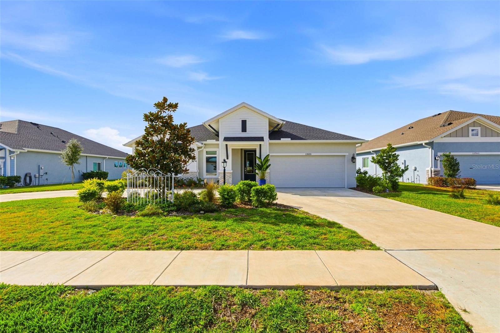 This 2023 David Weekley Craftsman-style pool home offers 2,847 square feet of refined living, a four-bedroom layout with a dedicated bonus room, three full bathrooms, and a three-car tandem garage—designed for both elevated everyday living and effortless entertaining.Arriving at 12889 Oak Street, the home immediately makes an impression with lush Florida-friendly native landscaping and an expansive circular driveway that sets a refined, private tone. Architectural awnings and a generous covered front porch draw you toward the glass front door, offering a preview of the craftsmanship and thoughtful design that continue inside.Stepping through the entry, natural light pours across the open interior, complemented by recessed lighting that highlights the clean lines and modern finishes. Just off the foyer is a versatile bonus room—perfect as a study, den, or office—followed by an expansive laundry room featuring ceramic tile flooring and a built-in folding table. Along this same hallway, a custom built-in shelving system functions as a stylish mudroom, adding both convenience and organization.Bedrooms two and three are located nearby, each generously sized with large built-in closets and access to a beautifully finished full bathroom with quartz countertops and modern fixtures. Down a separate hall, bedroom four offers privacy for guests and features its own ensuite bathroom, also appointed with quartz surfaces and contemporary finishes.The heart of the home is the kitchen, designed to impress with solid wood soft-close cabinetry, a striking backsplash, quartz countertops, a built-in oven, cooktop with range hood, stainless steel appliances, and an oversized island with seating. An expansive pantry and dedicated coffee bar complete the space, seamlessly connecting form and function.The dining and living room combination is anchored by a stunning chandelier and offers ample room for entertaining. A side entry door and large glass sliders extend the living space outdoors. Just beyond the living area, the primary suite provides a peaceful retreat with tray ceilings, serene views of the backyard, and a custom walk-in closet system. The primary ensuite bath features a dual-sink quartz vanity, modern fixtures, a soaking tub, and a glass walk-in shower.Outside, the private oasis truly shines. The one-year-old pool features a splash pad, water feature, and LED lighting, all framed by a paved lanai with recessed lighting and a fully screened enclosure with an infinity view overlooking the community seating area. Home is also equipped with generator hook up on the side of the home. The community is conveniently located near a state park and Mirada Lagoons, with easy access to SR 52 and Curley Road. Dade City is just 12 minutes away, offering shopping, dining, and local charm nearby. Schedule your private showing today, or explore the virtual tour through the provided link.