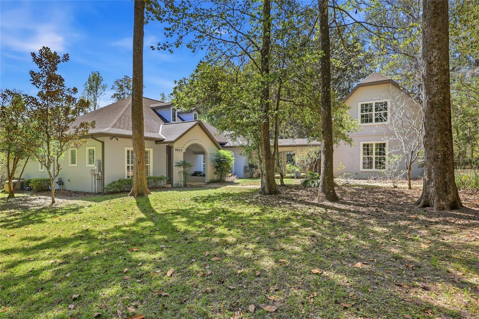 Privacy, water views, and room to enjoy the outdoors define this beautifully updated single-story estate located at the end of a quiet cul-de-sac in the highly desirable community of The Hammock in Northwest Gainesville. Offering 3,013 square feet of living space on 2.27 acres just off scenic Millhopper Road, the property combines peaceful surroundings with convenient access to the University of Florida and UF Health Shands Hospital, approximately 23 minutes away. Mature trees frame the home, which is positioned to capture tranquil views of a private lake and visiting wildlife. Inside, fresh interior paint, updated lighting, and new LVP and tile flooring create a clean, modern feel throughout. The practical split floor plan includes three bedrooms plus a dedicated home office, with two bedrooms able to close off behind a pocket door to create a private wing. The main living area features a gas fireplace and large doors that fully collapse open, seamlessly connecting the living room to an expansive screened deck overlooking the water. The kitchen offers excellent storage with a large walk-in pantry, while the oversized laundry room with sink adds everyday convenience. The primary suite includes two walk-in closets and peaceful views of the surrounding property. Additional highlights include a three-car garage with stairs leading to unfinished storage above, a covered breezeway connecting the garage to the home, and a spacious screened deck designed to enjoy the natural setting. Located near Devil’s Millhopper Geological State Park and San Felasco Preserve State Park, this property offers a rare opportunity to own acreage, privacy, and lakefront scenery in one of Gainesville’s most scenic areas.
