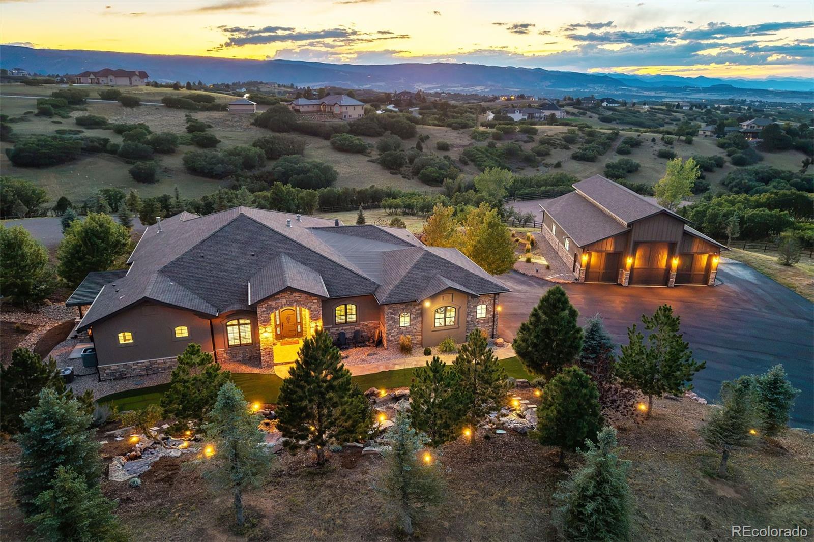 A home made for living it up. Designed for entertaining & large gatherings, this mountain contemporary home combines impressive scale with warmth, character & an unmistakable sense of fun, set against mountain views. It skips the cookie-cutter script. A 60-by-40 heated workshop with an oversized RV door is a dream space for hobbies, tools or toys. Set on one of Keene Ranch's quietest streets & configured into the hillside, the residence virtually disappears from the road, revealing privacy & views of the mountains & Dawson Butte. Beyond the private gate, motor court, landscaping & new asphalt driveway, 10 waterfalls cascade at the entry with all the drama of a Bellagio-style water feature. The kitchen is one of the largest in Keene Ranch! 3 islands create distinct spaces for cooking, prep & gathering: one anchored by a Viking range & hood, one with a prep sink & storage, & one overlooking the great room. 6 ovens, a built-in pizza oven, & Viking Professional & Miele appliances make this a kitchen built for family dinners & unforgettable parties. It flows into the dining room & great room, where a stone fireplace & reclaimed barn wood wall bring warmth & character. The main-level primary suite offers 2 separate bathrooms & walk-in closets, each with laundry, plus a private deck with pergola. 2 more bedrooms & an office complete the main level; a fourth bedroom is downstairs. Take the elevator down, where the fun continues. A recreation room combines a sitting area with a home gym, while a media room offers a potential home theater, currently an office/music room. At the end of the hall, a vault door opens to an unexpected private speakeasy with a 16-foot bar, shuffleboard table, darts, ice maker, fridge, dishwasher & bathroom. A feature guests will talk about long after the party ends. A covered, heated lower patio with hot tub offers another place to relax, while the upper deck with motorized sun shades sets the stage for the views.