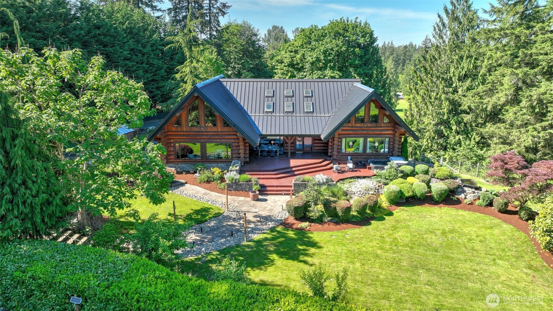 Tucked away on nearly 10 acres of beautifully maintained grounds, this extraordinary log home offers a rare blend of timeless craftsmanship, natural beauty, and modern comfort. Rich wood finishes, soaring 25-foot ceilings, and walls of windows frame peaceful territorial views, while the dramatic great room is anchored by a handsome stone gas fireplace designed for both everyday living and entertaining. The chef’s kitchen features an oversized honed granite island, stainless steel appliances, abundant workspace, and seamless flow into the dining and living areas. Indoor-outdoor living comes naturally with expansive entertaining spaces, a covered area for year-round enjoyment, and an 8-person hot tub surrounded by the beauty of the property. The main-level primary suite offers the convenience of main-floor living, while two additional bedrooms upstairs provide flexibility. The lower level includes two non-conforming rooms ideal for hobbies, office space, guests, or additional living needs. Recent updates include new flooring, appliances, water heater, whole-home generator, water filtration system, well pump, garden installation, and new back and side decks. Outside, you’ll find fruit trees, a lovely greenhouse and raised garden beds, RV parking, a koi pond and sprawling acreage, creating a true Pacific Northwest retreat. A one-of-a-kind property offering privacy, livability, and room to explore.