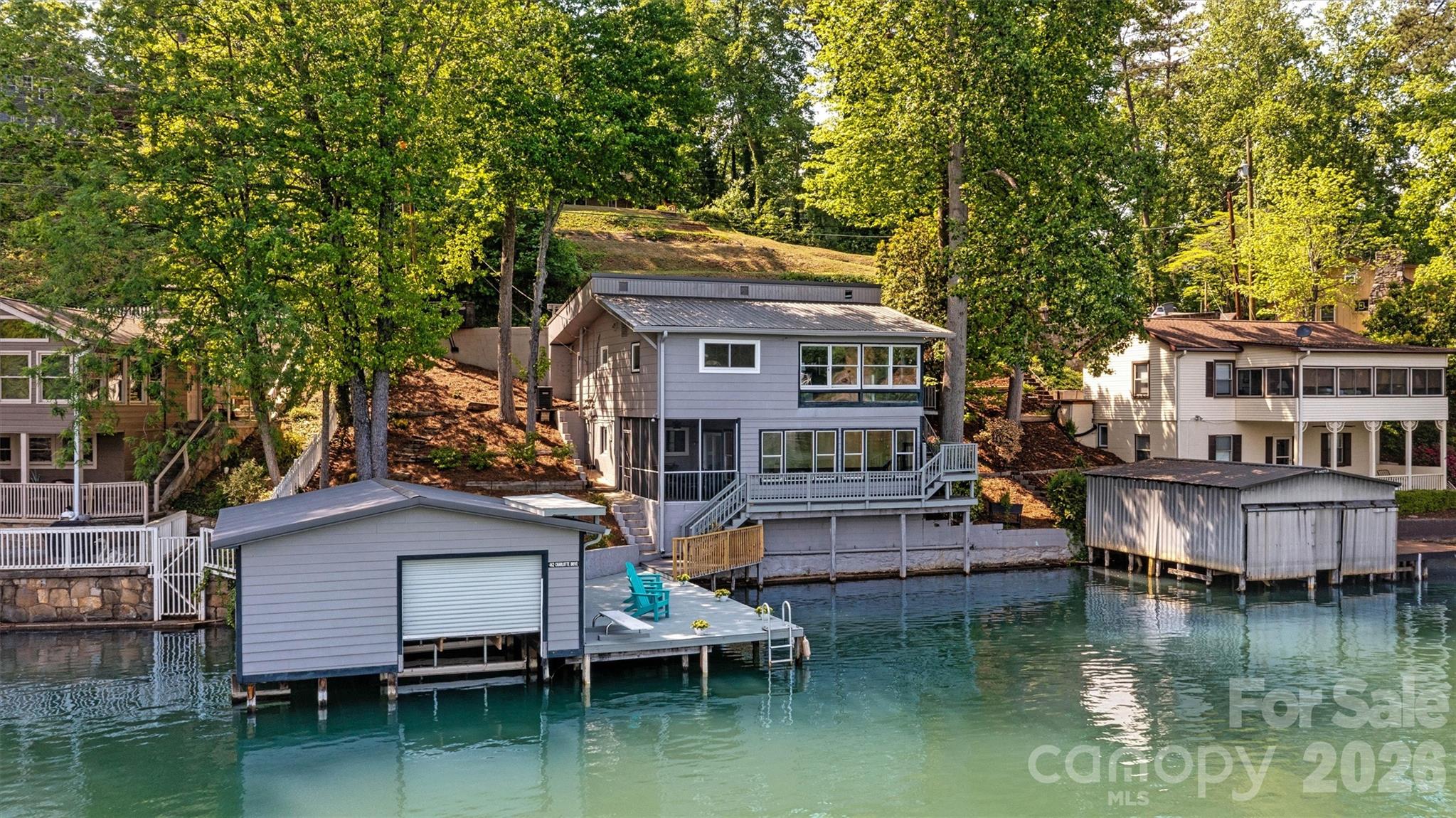 Fully Furnished, turnkey, impeccably maintained waterfront retreat on Lake Lure, showcasing sweeping, unobstructed BIG lake views. This exquisite three-bedroom, two-bath residence offers an exceptional blend of comfort and elegance, perfectly positioned at the water’s edge with deep water access directly off the private dock. A covered boathouse provides generous storage for watercraft and lake accessories. The main level features a serene primary suite and a beautifully renovated open-concept kitchen flowing seamlessly into the great room, anchored by a charming wood-burning fireplace. Sunlight pours into the inviting sunroom, where mornings begin with coffee and panoramic lake vistas that create the sensation of living directly on the water. The lower level offers two additional guest bedrooms, a full bath, a versatile flex space, and a conveniently located laundry closet—ideal for hosting family and friends. Outdoor living is elevated with a screened porch perfect for al fresco dining, while the private dock invites relaxation as boats glide by on the lake. A rare opportunity to own a thoughtfully designed Lake Lure home where timeless luxury meets effortless lakefront living.