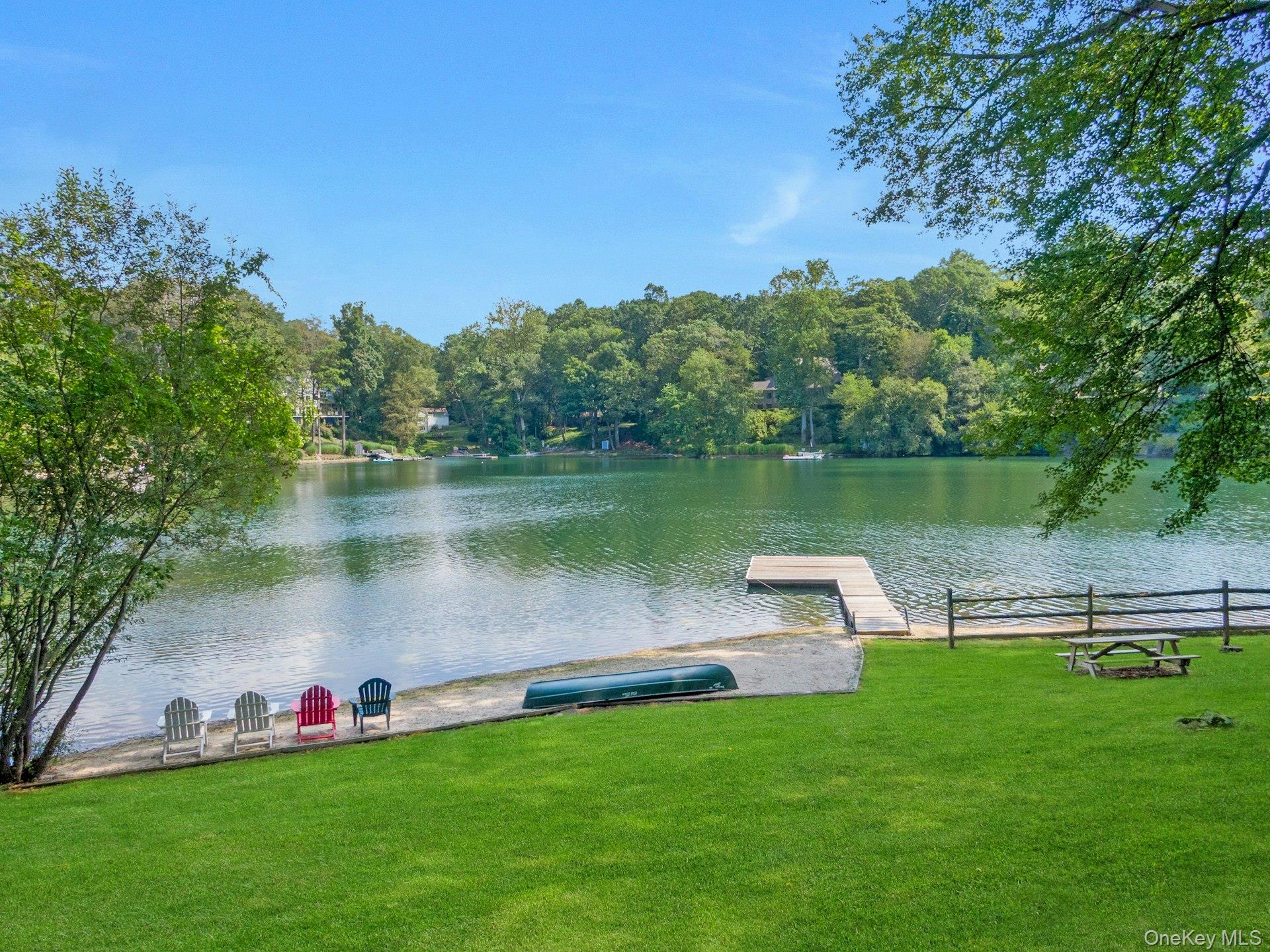 A dazzling opportunity to own an epic property in Armonk’s coveted Windmill Farm community, privately set behind its own gate on 1.2 acres. This rare North Lake waterfront home offers just under 5,300 sq ft of living space and over 220 feet of shoreline on 22-acre North Lake, with a private dock for swimming, boating, and fishing, plus spectacular views from almost every room. A lovely, gently sloping lawn stretches from the house to the water’s edge, creating a serene, park-like setting.
Thoughtfully custom-built with quality finishes, the home features a charming rocking chair front porch, sun-filled open spaces, and a comfortable flow ideal for both lively entertaining and everyday family living. Two stone patios overlook the lake—perfect for summer gatherings—while a beautiful balcony off the primary bedroom is an inviting spot to enjoy your morning coffee or a good book. A sandy beachfront invites you to build sandcastles, sink your toes in the warm sand, and savor the simple joys of lakefront living. From summer kayaking to winter ice-skating, every season offers a new way to enjoy this one-of-a-kind setting—just minutes to Byram Hills schools, downtown Armonk, and Metro-North, and only an hour from NYC.