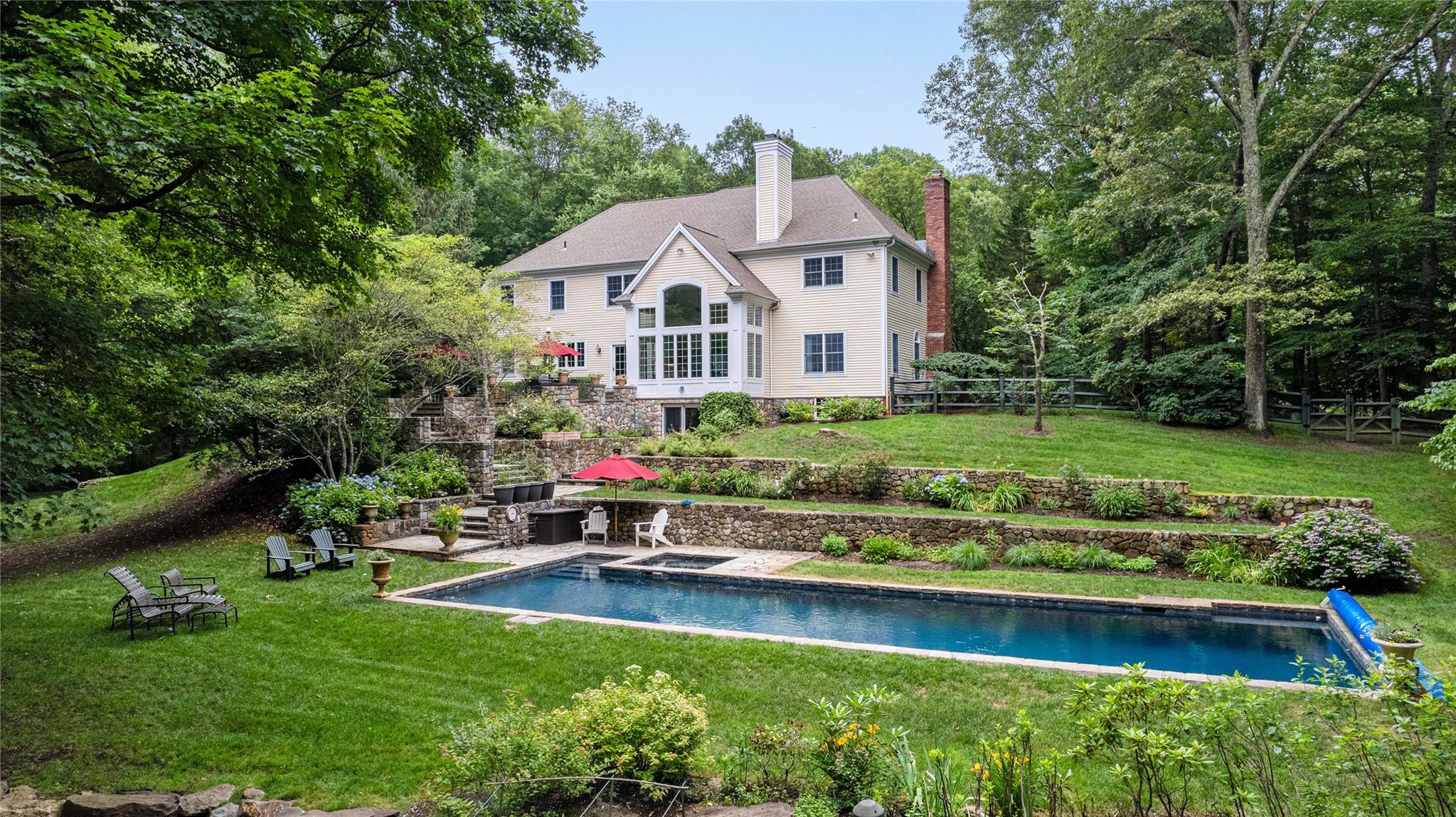 Welcome home to this beautiful colonial, perfectly situated in a spectacular private setting that backs up to the pristine Mianus River Gorge. These original owners thoughtfully designed and customized the home with high-end finishes and exceptional attention to detail throughout. The heart of the home is a recently renovated kitchen, featuring a gas cooktop, custom cabinetry, stone countertops, and a calming natural palette that seamlessly blends style and function.

The open-concept family room is filled with natural light from a striking Palladian window overlooking the backyard, and is anchored by a classic wood-burning fireplace that creates a warm and welcoming gathering space. The gracious foyer sets an elegant tone upon entry, flanked by a formal living room ideal for entertaining, and a private den or office perfect for work-from-home needs or quiet study.

Upstairs, you’ll find four spacious bedrooms thoughtfully arranged for both comfort and privacy. The luxurious primary suite serves as a true retreat, with a newly remodeled spa-inspired bath featuring a soaking tub, double vanity, and separate glass-enclosed shower — creating a peaceful oasis for relaxation. Two separate walk-in closets provide abundant storage and organization. This primary suite is located on the same level as the other three bedrooms, but thoughtfully set apart to ensure privacy and tranquility.

A walk-up attic with full flooring provides generous, easily accessible storage, while the finished lower level offers over 1,000 square feet of versatile space and walks out directly to the pool area.

Outdoors, the property is a true showstopper. The beautifully landscaped yard includes a stunning heated 16x54 gunite pool with a solar cover for energy efficiency. This pool area feels like a private resort, surrounded by lush landscaping, mature trees, and classic stone walls that provide both natural beauty and a sense of peaceful seclusion. The spacious patio off the kitchen is ideal for al fresco dining and summer gatherings, while the large, level lawn offers endless possibilities for play and recreation, all set against a backdrop of serene woodland views.

Additional highlights include a full-house generator for peace of mind, an oversized two-car garage, and pride of ownership evident throughout. Crisp, fresh, and thoughtfully maintained, this colonial is ready to welcome its next owner to enjoy its exceptional setting and timeless appeal.