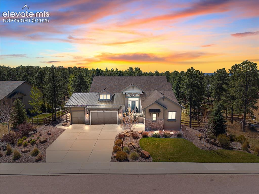 Located in the highly sought-after Sanctuary Pointe community in Monument, this exceptional Vantage Homes Riverwood floor plan backs directly to Fox Run Regional Park with no rear neighbors and sits on nearly 1/2 acre among towering Ponderosa pines. Recently enhanced with fresh interior and exterior paint, a new 708 sq ft maintenance-free exterior deck, newly poured covered patio, commercial-grade epoxy garage flooring, and the addition of a bedroom and bathroom, this home blends thoughtful updates with quality construction. This true 5-bedroom, 5-bathroom layout features two main-level en-suite bedrooms and three lower-level bedrooms, including an additional en-suite. The open main level offers soaring ceilings, abundant natural light, a dramatic floor-to-ceiling stacked stone gas fireplace, and expansive sliding doors leading to the oversized deck overlooking the peaceful wooded setting. The kitchen features granite countertops, double ovens, an oversized island, extensive cabinetry, and a hidden walk-in "Narnia" pantry, while the dining area captures beautiful backyard views. The walkout lower level includes a custom wet bar with floor-to-ceiling stacked stone detail, live-edge wood countertop, spacious entertainment room, and direct access to the covered patio. The fully insulated 4-car garage includes commercial-grade epoxy flooring. Raised garden beds, mature landscaping, fencing, and a storage shed complete this exceptional property, located minutes from shopping, dining, and I-25.