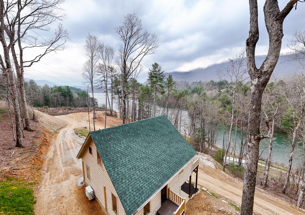 Welcome to your dream mountain retreat in the newly developed Deer Run Estates, a gated community offering privacy, beauty, and coveted lake access. This brand-new 2-bedroom, 2.5-bath cabin with a spacious loft perfectly blends modern comfort with rustic charm. Designed with a true cabin feel, the home features log siding, log railings, rich wood floors, solid wood doors, and stunning interior wood ceilings that create a warm and inviting atmosphere throughout. The open-concept living space is ideal for relaxing or entertaining, while the thoughtfully designed layout provides both functionality and comfort. A tankless propane water heater ensures efficiency and endless hot water for everyday living. Positioned to face west, this cabin captures breathtaking sunset views over the lake and surrounding mountains, making every evening unforgettable. Located in a natural paradise, this property is a haven for outdoor enthusiasts, with endless opportunities for hiking, boating, and exploring nearby wilderness. Just minutes from Santeetlah Marina, and conveniently close to the renowned Tail of the Dragon and the serene Joyce Kilmer Memorial Forest, adventure is always within reach. Whether you're seeking a full-time residence, vacation escape, or investment property, this exceptional lake-view cabin offers the perfect combination of tranquility, craftsmanship, and access to the great outdoors.