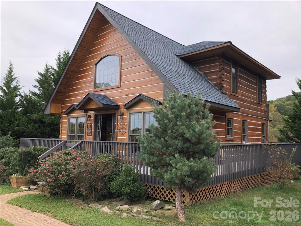 Idyllic log cabin in high demand exclusive Cane Creek Valley Fletcher/Fairview area with year round creek in the woods. Wraparound deck goes completely around house. Hot tub off main bedroom overlooking stream and distant mountains with peaceful, tranquil valley view. Main bedroom and laundry on main level. Main bath has claw foot tub and whiskey barrel/ copper sink. Lots of windows in all of the right places. Open great room with gas log woodstove, spacious kitchen with island and granite countertops. Dramatic cathedral ceilings with loft that has 2 bedrooms, full bath and large walk-in closet. Main upper bedroom has large private balcony deck. Area of new homes. Excellent sun exposure with long range views. Two custom built carports with concrete floors and storage/workshop. Close to South Asheville's mega shopping and airport, near I 26.  Square footage from tax records, to be measured. Property includes privacy rows of Leyland cypress on both side of house and carports.