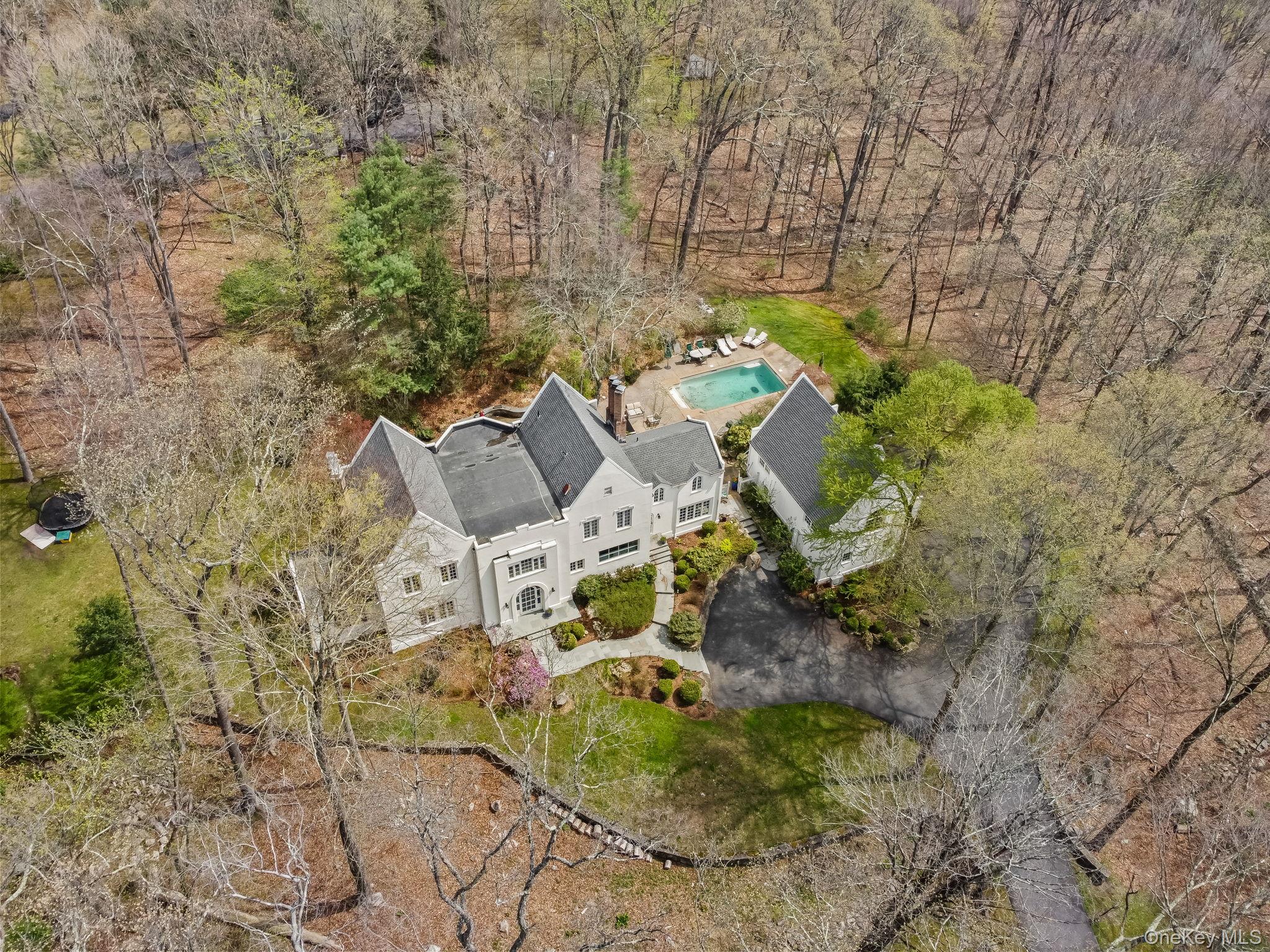 This beautifully appointed, grand and stylish Colonial seamlessly blends grand-scale entertaining with intimate everyday living. Highly sought after location at the end of a quiet cul-de-sac, the home offers exceptional privacy while remaining just minutes from Bedford Village, Scotts Corners, and acclaimed Jean-Georges’ Inn at Pound Ridge. New Roof, New kitchen and appliances including washer/dryer, new bathrooms, new siding, new mechanicals such as condensers, oil tank and lines, tankless water heater, updated saltwater gunite pool system, new driveway and lights up driveway, new walkway and masonry, new windows, new side door and back patio doors, landscaping, new garage doors. Thoughtfully laid out with a designers aesthetic, beautifully renovated kitchen and baths, exposed beams and high vaulted ceilings showcase the highest level of craftsmanship throughout. Highlights include custom millwork and cabinetry, rich hardwood floors, romantic fireplaces, top-tier appliances and 3 car garage. The expansive primary suite is a true WOW, with vaulted ceilings, walk in closet and lovely fireplace seating area complemented by 3 additional sun-filled bedrooms.A separate guest house with kitchen and bath—ideal as a studio, pool house, or private workspace—adds versatility to the property. Outdoors, a sparkling heated pool is perfectly set within a picturesque, beautifully landscaped retreat, creating a true country escape.