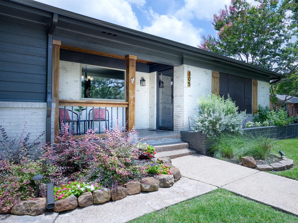Welcome to 305 Martha Manor — a beautifully maintained mid-century gem in Richardson, TX that perfectly blends timeless character with modern updates. This 1,930 sq ft, 3-bedroom, 2-bathroom home with a bonus room delivers an exceptional combination of charm, space, and outdoor living that is truly hard to find. Step inside to find rich hardwood floors flowing throughout the main living areas, crown molding, and an abundance of natural light pouring in from multiple windows. The spacious living room opens seamlessly to a formal dining area with a classic chandelier, creating an ideal layout for both everyday living and entertaining. The kitchen features maple cabinetry, granite countertops, a peninsula with bar seating, stainless steel gas range, and pendant lighting — all opening to the dining space for a connected, functional flow. The primary suite is a true retreat, boasting its own cozy fireplace with a classic white mantle, wainscoting detail, ceiling fan, and a connected bonus room — perfect as a sitting area, home office, or flex space. The updated bathrooms include a beautifully renovated bath featuring a frameless walk-in shower with marble-look tile, shaker-style cabinetry, granite countertops, and shiplap wainscoting with brushed nickel fixtures throughout. Outside, the home truly shines. The expansive covered back patio with exposed wood beam ceiling, ceiling fan, and pendant barn light creates an incredible outdoor living space. A large concrete driveway provides ample parking, all within a fully fenced backyard with a private electric gate. The detached 2-car garage completes this exceptional outdoor package. The charming covered front porch, striking white brick exterior with dark accents and wood beam details, and meticulously maintained landscaping with mature trees create impressive curb appeal. Close to schools, shopping, highways and more!