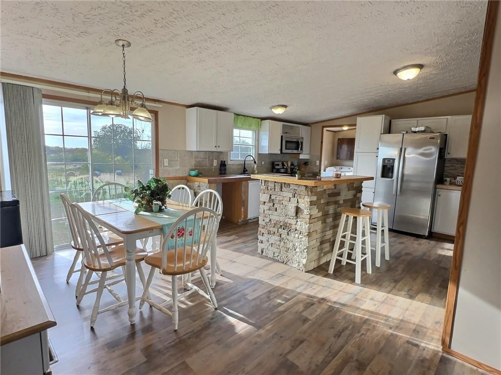 OH MY LAND!! Discover the perfect blend of modern comfort and country living on this 20-acre mini farm. The property's centerpiece is a lovely 2006 Clayton manufactured home, designed with a spacious and bright 4-bedroom, 2-bath open-concept floor plan that is ideal for family life. The kitchen flows seamlessly into the living areas, creating an inviting space for gatherings. The home has a newer ground source heat pump for very efficient heating and cooling. It also comes with a stainless-steel appliance package. This home is a VA and FHA financing contender.
Step outside to explore your private 20 acres, featuring a serene pond and a reliable well. The property is mostly fenced, providing a safe haven for animals or simply a quiet space to enjoy nature. Located just across the road from the Wah'kon-tah Prairie Conservation Area, you will have a front-row seat to the beauty of the tallgrass prairie and the abundant wildlife it supports. The property's existing deer population makes it a fantastic hunting spot.
For the hobbyist or tradesperson, a generously sized workshop offers a dedicated space for any project. An additional older mobile home with a concrete patio and a root cellar presents an exciting opportunity for restoration. Imagine using it as a seasonal hunter's cabin or as a comfortable guesthouse, creating a multi-generational living space or an income-generating rental.