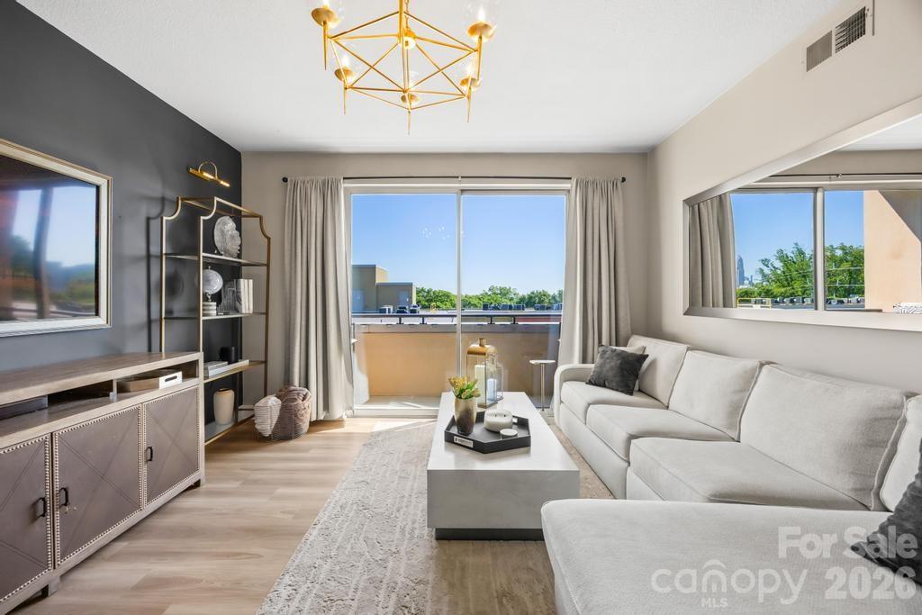 Perched on the 7th floor in the heart of Dilworth, this updated condo pairs clean modern finishes with an easy walkable lifestyle. Open living and dining spaces flow seamlessly from the kitchen with white cabinetry, tile backsplash, bar seating, and stainless appliances, while oversized windows and sliding doors bring in natural light throughout. The living room opens to a private covered balcony overlooking the surrounding neighborhood. Split bedroom layout offers added privacy, including a spacious primary suite with walk-in closet, dual vanity bath, and large windows, while the secondary bedroom sits adjacent to a full hall bath with updated finishes. Vinyl plank flooring runs through the main living areas, with in-unit laundry tucked conveniently in the hall. Secure gated underground parking includes 2 assigned spaces, plus access to rooftop terrace, fitness center, courtyard spaces, elevator, and all that East Blvd dining, shopping, and Uptown access have to offer.