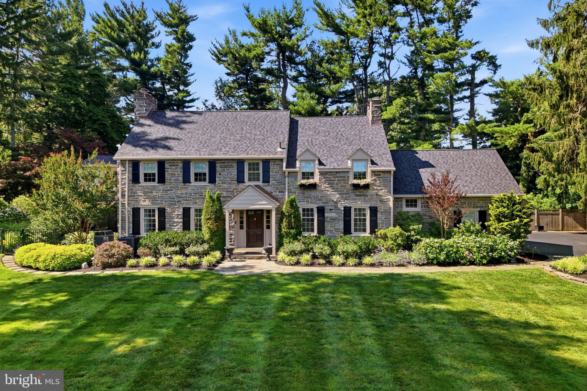 Set privately on one beautifully landscaped acre in the heart of Penn Valley, 735 Righters Mill Road is a classic 1937 stone Colonial that pairs the character and craftsmanship of an earlier era with a thoughtful expansion designed for modern living.  Offering more than 5,700 finished square feet, five bedrooms and five and one half baths, the home retains many of its original architectural details, including handsome millwork, hardwood floors and three fireplaces. Significant updates and a 2009 expansion introduced a more open floor plan, vaulted ceilings and generously scaled spaces for both everyday living and entertaining.  At the center of the home is a beautifully appointed kitchen with a large center island and adjacent butler’s pantry, opening naturally to the surrounding living spaces. A formal dining room provides an elegant setting for more traditional entertaining, while the screened porch overlooking the gardens offers an inviting place for relaxed dining, reading or simply enjoying the landscape through much of the year. Additional gathering spaces include a billiards and bar area, while two separate offices offer welcome flexibility for working from home.  Two primary suites, one on the first floor and another on the second, provide unusual versatility for changing needs, extended family or guests. A separate rear staircase leads to a private guest suite, further enhancing the home’s thoughtful and highly adaptable floor plan.  The grounds are an exceptional complement to the architecture. Mature specimen trees and plantings, continuously blooming perennials and two water features create an arboretum-like setting that feels established, private and remarkably serene. An irrigation system helps maintain the extensive gardens, while thoughtfully placed landscape lighting transforms the property after dark. Fenced rear and side yards add another layer of privacy, and the home’s position on the property creates a welcome sense of separation from both the road and neighboring residences.  Remarkably convenient yet quietly removed, the property is close to Main Line schools, parks, playgrounds, the library and community pool, as well as shopping, dining and transportation. Center City Philadelphia is within easy reach.  With its enduring stone architecture, gracious proportions, flexible living spaces and beautifully cultivated grounds, 735 Righters Mill Road offers the increasingly rare combination of Main Line character, privacy and ease of living.