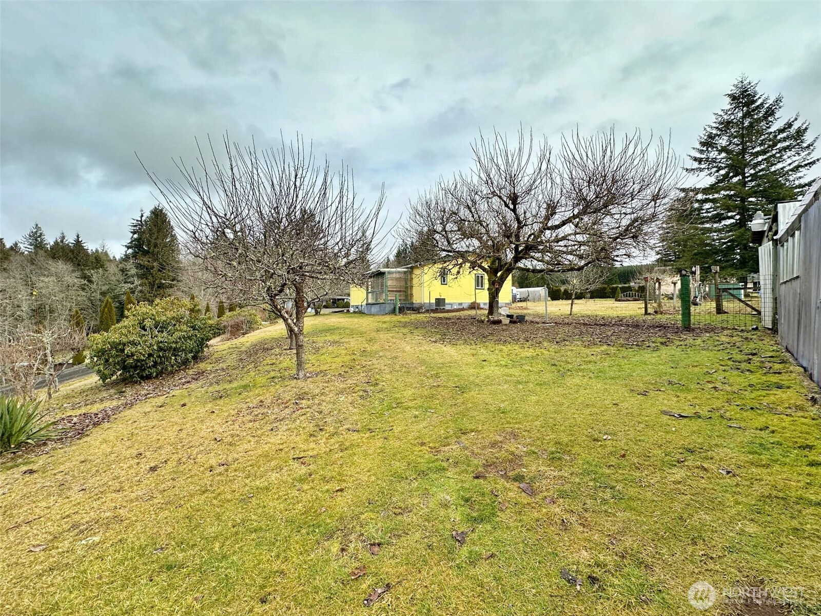 Discover your peace & quiet in This comfortable 2/3 bedroom, 1.75-bathroom home. Bonus room for work at home! All on a  1.19-acre lot. Enjoy outdoor living with a fenced yard, a lovely garden space, plenty of fruit trees, a greenhouse, and a quiet, secluded setting. Additional features include a 1152 sq ft shop with an ADU, perfect for guests or hobbies. Step out of the fast lane and slow down on this dead end road, wildlife all around, enjoy a walk in the woods--schedule your tour today.