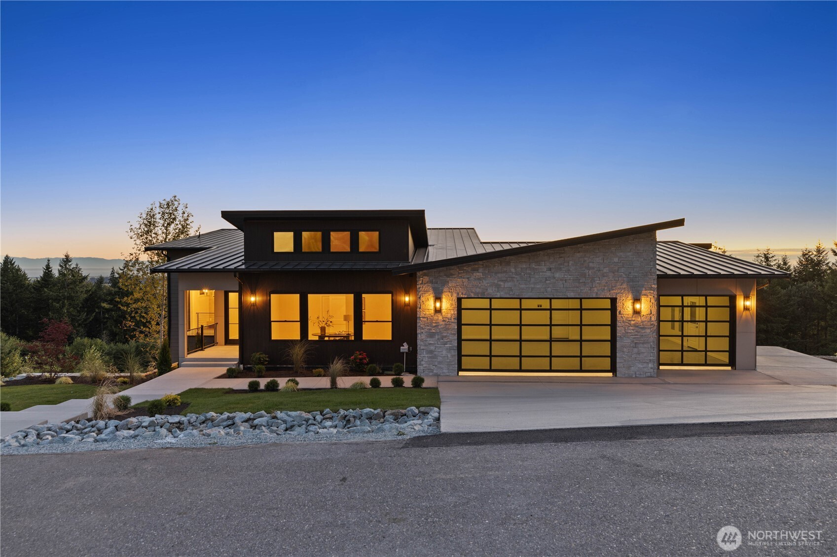 Introducing a brand new Saratoga Passage View residence! Perched above the Skagit Valley on a private acre along a quiet dead-end street with grand water and valley views. 3,908 square feet pair main level living with a full daylight lower level. The vaulted great room is anchored by a floor-to-ceiling custom fireplace, floating oak mantel and a wall of glass framing Puget Sound and the Olympic mountaintops. The chef's kitchen showcases two-tone oak and white cabinetry with Taj Mahal quartzite wrapping the waterfall island, backsplash and butler's coffee bar, plus over-sized gas range, double ovens, pot filler and walk-in pantry. The primary suite offers a fireplace and a spa-inspired bath where a freestanding soaking tub sits beneath a valley view picture window, with dual vanities, makeup station and an expansive triple head walk-in shower. A custom-fitted walk-in closet finishes the retreat, and heated tile floors warm each bath. Downstairs, 2 additional bedrooms with en suite baths join a recreation room with wet bar, flex room, second laundry and ample storage, for 4 bedrooms and 4 baths. The upper covered deck with cedar ceiling, outdoor kitchen and overhead heaters invites year-round entertaining, sheltering a lower deck with steps to the yard. A finished three-car garage with epoxy floors and EV charging hooked up + generator wiring completes the home. Conway schools and minutes to I-5, downtown Mount Vernon and the heart of Skagit Valley. Come tour!