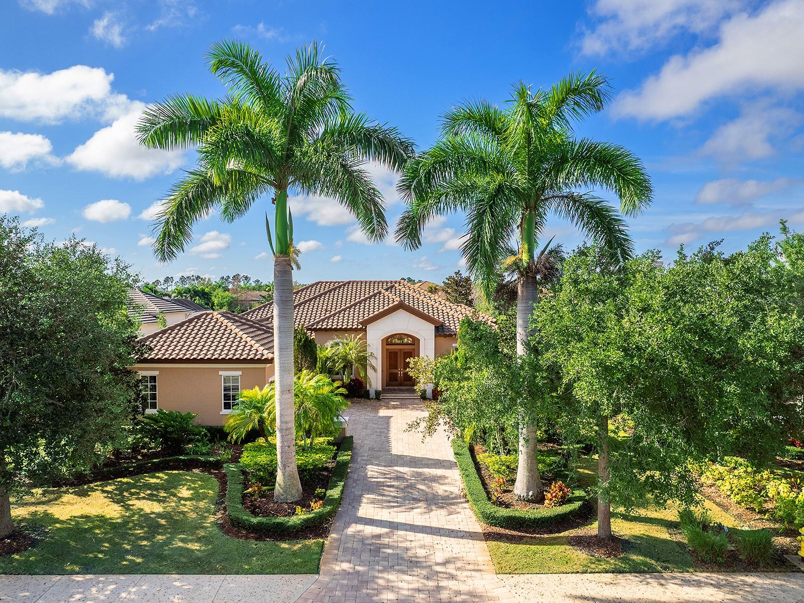 Ready for a completely custom, lakeside lifestyle in one of the premier communities of Lakewood Ranch? Now available in The Lake Club is this custom Todd Johnston residence that is brimming with contemporary style, sparkling lake views, and the little touches throughout the home that make living here a true joy. Located in the original phase of The Lake Club, you’ll arrive home from the gated entrance to streets lined with mature palms and oaks, and you can take advantage of the proximity of the clubhouse and amenities. Boasting over 3,400 SF, this home has a space for every lifestyle, whether you enjoy formal entertaining, casual gatherings, or outdoor get togethers. From the solid double front door, you’re invited into the foyer where you get the first glimpses of the southwestern lake views and custom upgrades including porcelain tile flooring; impact windows and sliders, designer light fixtures, custom feature walls, tray ceilings with sound system, and more. The formal living and dining spaces set the stage for holiday meals and elegant entertaining, or wind down with casual weeknights in the family room and dinette nook. The chef’s kitchen is truly the star of this home showcasing custom slab cabinetry, waterfall stone counters, peninsula seating, and a central island with prep sink, 2 wine refrigerators, and reverse osmosis system. The top-of-the-line appliance suite by Thermador makes cooking a breeze with a 6-burner gas cooktop, warming drawer, dishwasher, refrigerator, built-in steam wall oven, microwave, and your own coffee station with built-in Miele cappuccino machine. The family room is the ideal hang out space with a custom feature wall of art display niches and fireplace, plus two walls of sliding glass doors connecting you to the outdoors. The travertine paver lanai takes center stage with a completely custom pool that is truly a work of art with waterfall, sunshelf, and raised spa that maximizes the lake views. Surrounded by a classic colonnade screen enclosure, the lanai offers two separate covered entertaining areas and custom outdoor kitchen outfitted with stainless steel grill, separate side burner, bar fridge, and your very own pizza oven! Inside the spacious primary suite offers dual views of the lanai and pool, separate seating area, large walk-in closet with his and hers built-ins, and a custom morning bar so you don’t need to leave your bedroom for morning coffee. The en-suite bathroom is truly a spa experience with custom tile walls and floors, jetted soaking tub; vanity with extra storage, large built-in mirrored medicine cabinet, towel warmer, his and her’s private water closets, TV within the mirror and a spacious frameless glass walk-in shower with rain heads, body sprays, and steam. When you crave privacy, retreat to the study with custom leather-look floors and built-in storage cabinetry that is tucked away from the action of the home. There is even a large bonus room with lakes views and French doors to the lanai that offers a versatile space for a media room, hobby room, den, or anything your lifestyle desires. Guests will find comfort in their own spacious bedrooms complete with walk-in closets and en-suite bathrooms; one bathroom also offers additional access as a full pool bath. Completing this impressive residence is a laundry room, and 3-car side-loading garage. The Lake Club is an exclusive premier, gated community with a Grande Clubhouse, restaurant, pool, tennis, pickleball and more.