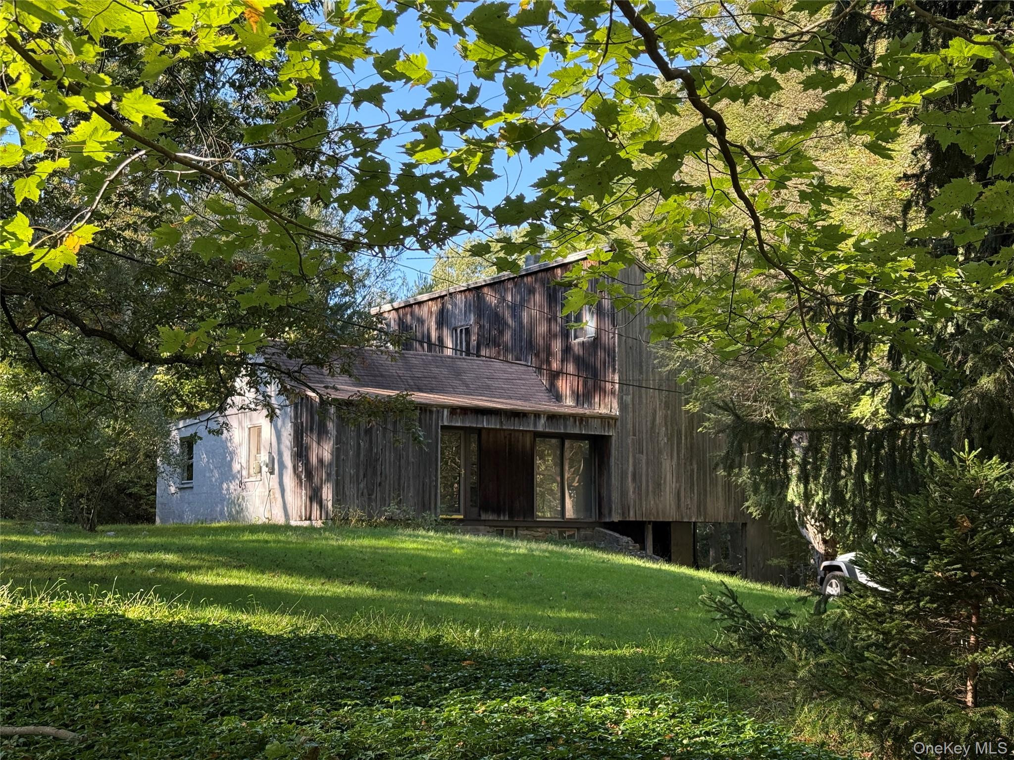 Endless possibilities await - restore, rebuild, or reimagine this serene Pound Ridge property and create the lifestyle you’ve been dreaming of. This remarkable 7-acre property, once home to horses and still featuring the remnants of a paddock and two-stall barn, is nestled near the end of a stonewall-lined driveway. The existing two-bedroom, one-bath residence with an unfinished modern addition (approximately 1,806 sq. ft.) offers a rare opportunity to own a country retreat.Surrounded by stately oaks, dogwoods, pines, and mountain laurel, the tranquil setting provides privacy, beauty, and space that are increasingly hard to find. The grounds of the property include a non-working inground pool and private walking trails through woodlands and dramatic rock outcroppings - ideal for creating an equestrian estate, a private sanctuary, or a weekend getaway.While the home is in significant disrepair, it provides an inviting canvas for those with vision. Property to be sold AS-IS condition. Perfectly located just minutes from the charming Pound Ridge town center - with its local shops, restaurants, and antique stores - and convenient to Bedford, South Salem, New Canaan, and Stamford, CT. Manhattan is just over an hour’s drive away.